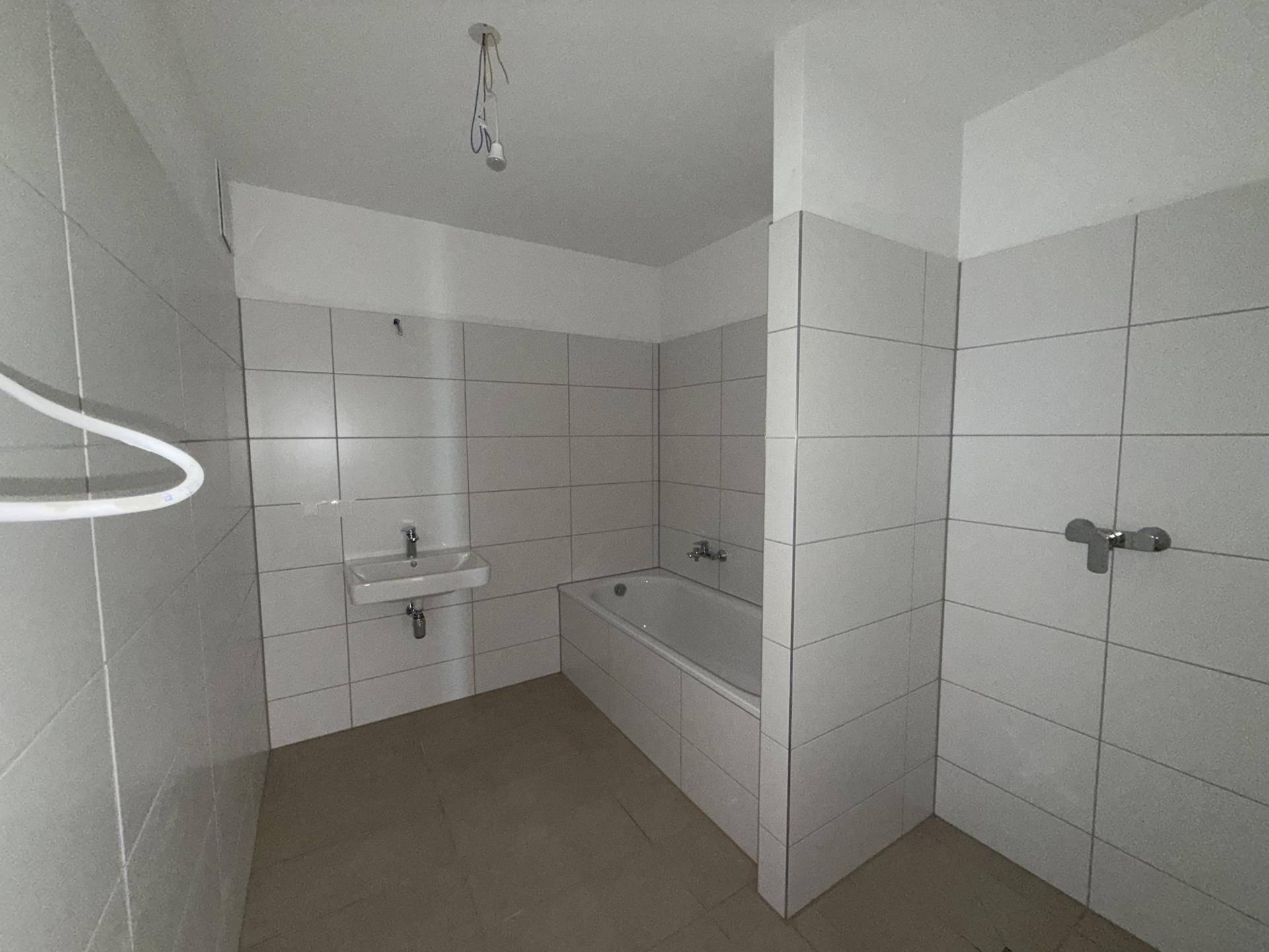 Modern gefliestes Badezimmer mit Badewanne, Waschbecken und einem separaten Duschbereich.