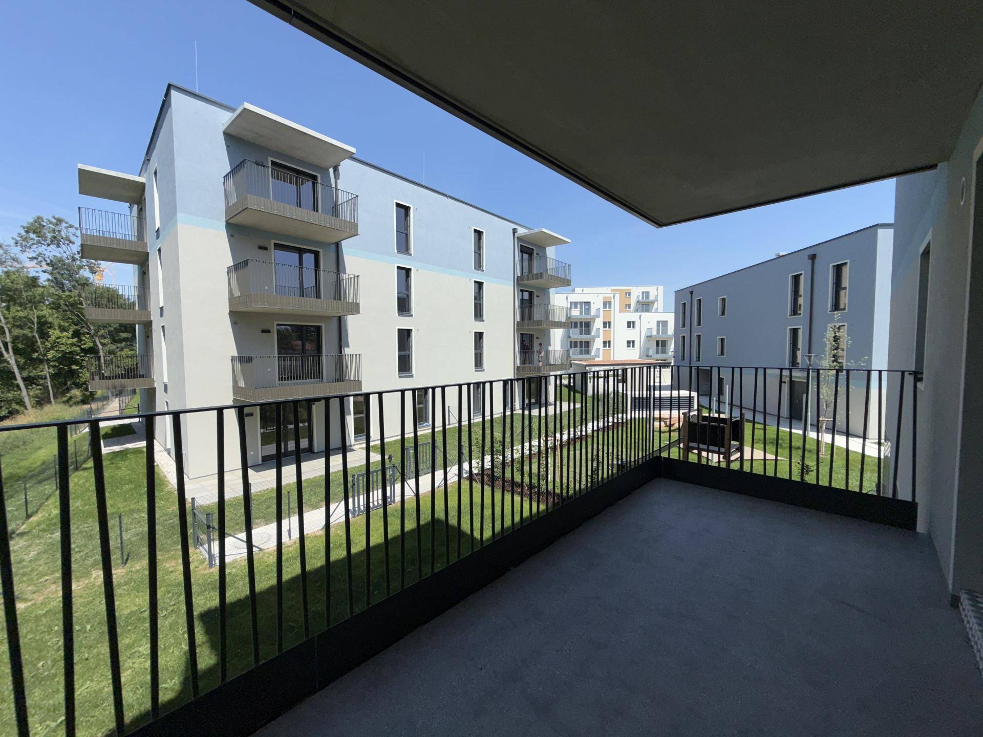 Geräumiger Balkon mit Blick auf die modernen Wohngebäude und die gepflegten Grünflächen der Anlage.