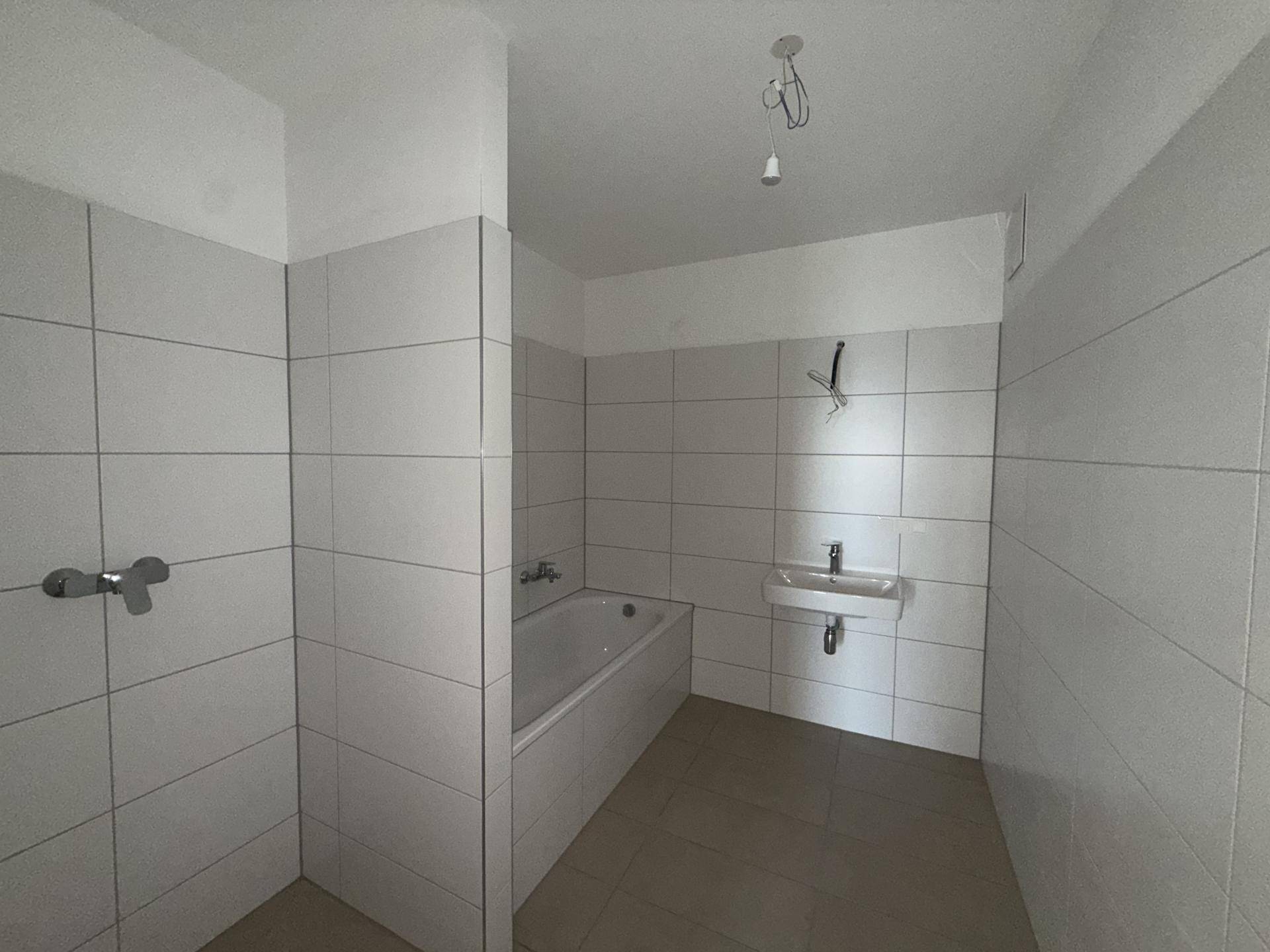 Modernes Badezimmer mit weißen Fliesen, Badewanne und einem einzelnen Waschbecken.