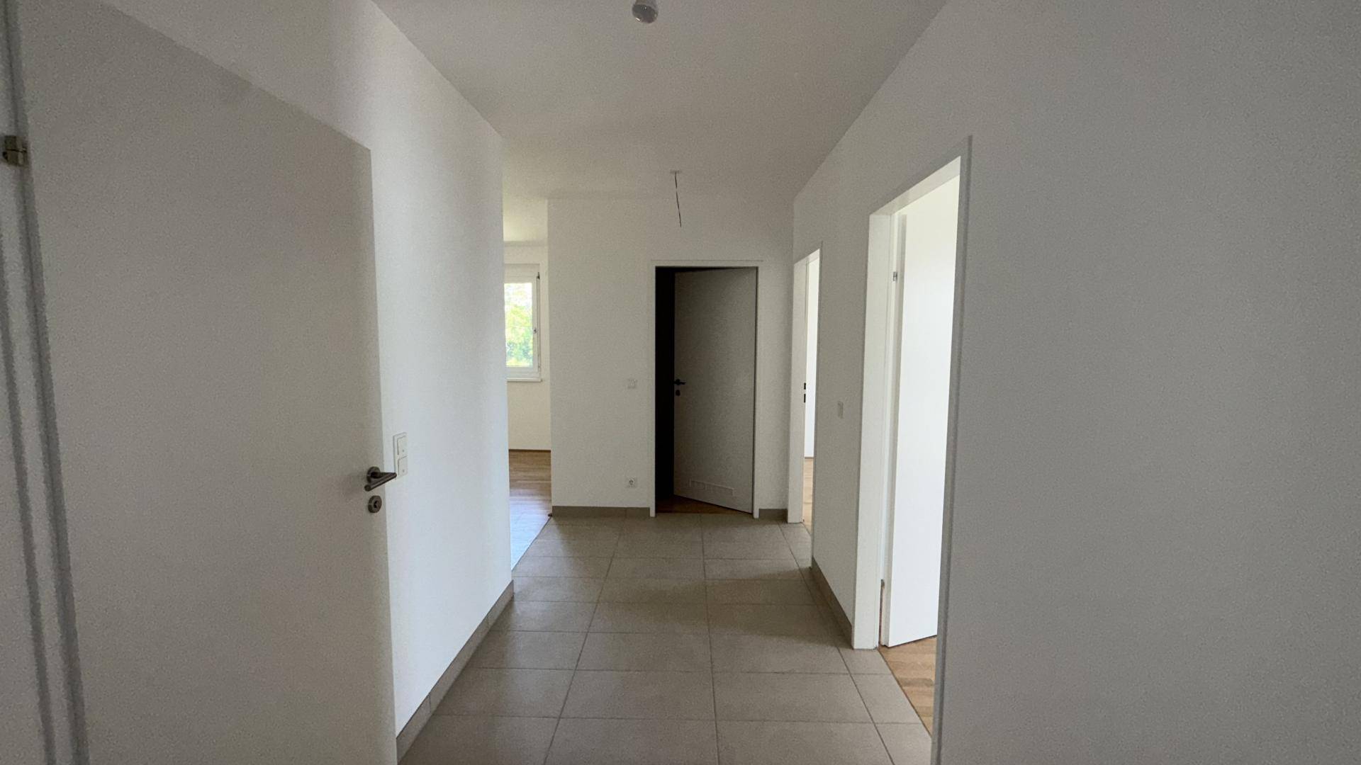 Heller Flur mit Fliesenboden und mehreren Türen, die zu verschiedenen Zimmern führen.