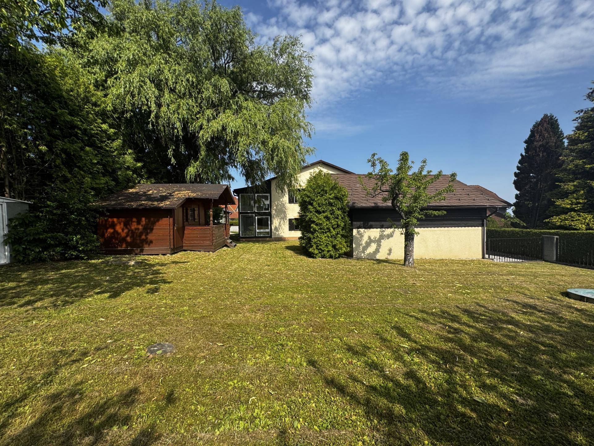 Weitläufiger Gartenbereich mit Gartenhaus, altem Baumbestand und viel Grünfläche.