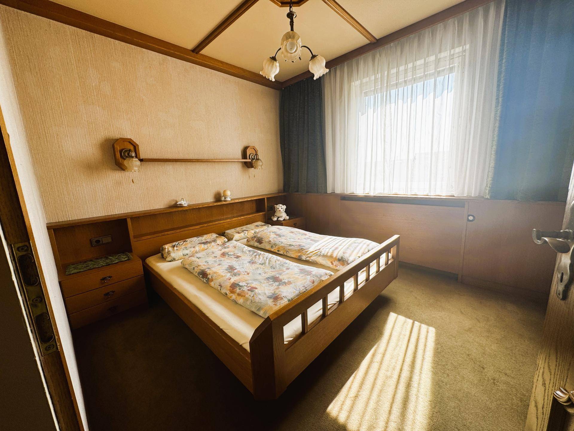 Schlafzimmer mit Holzdoppelbett, integrierten Nachttischen und Teppichboden.