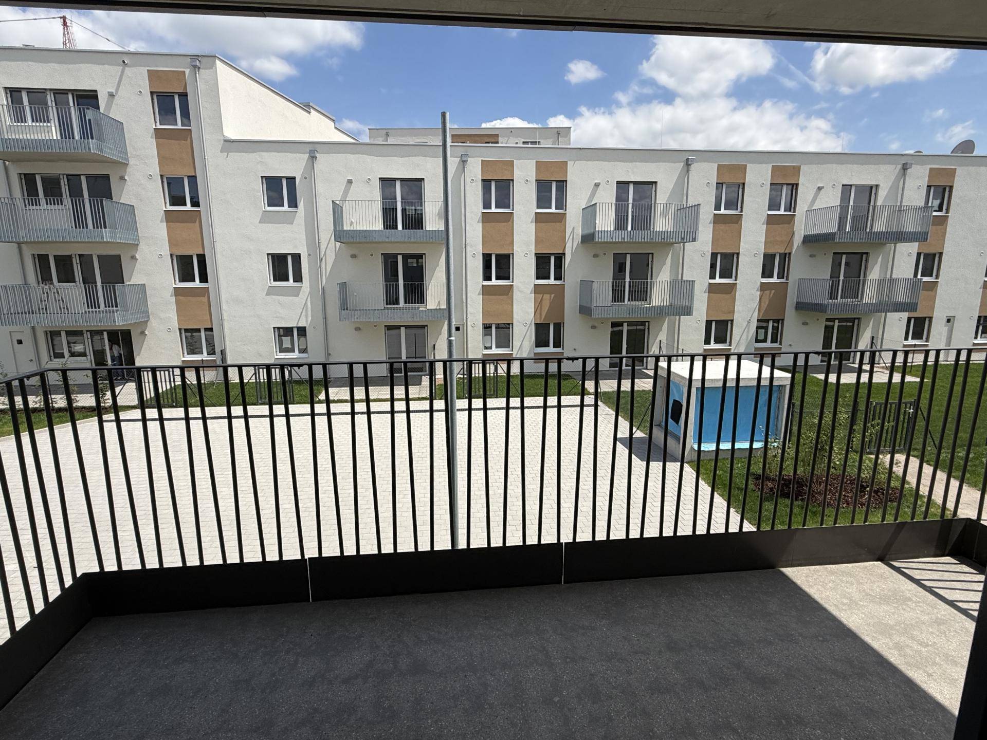 Blick vom Balkon auf die moderne Wohnanlage mit weiteren Balkonen und einem begrünten Innenhof.