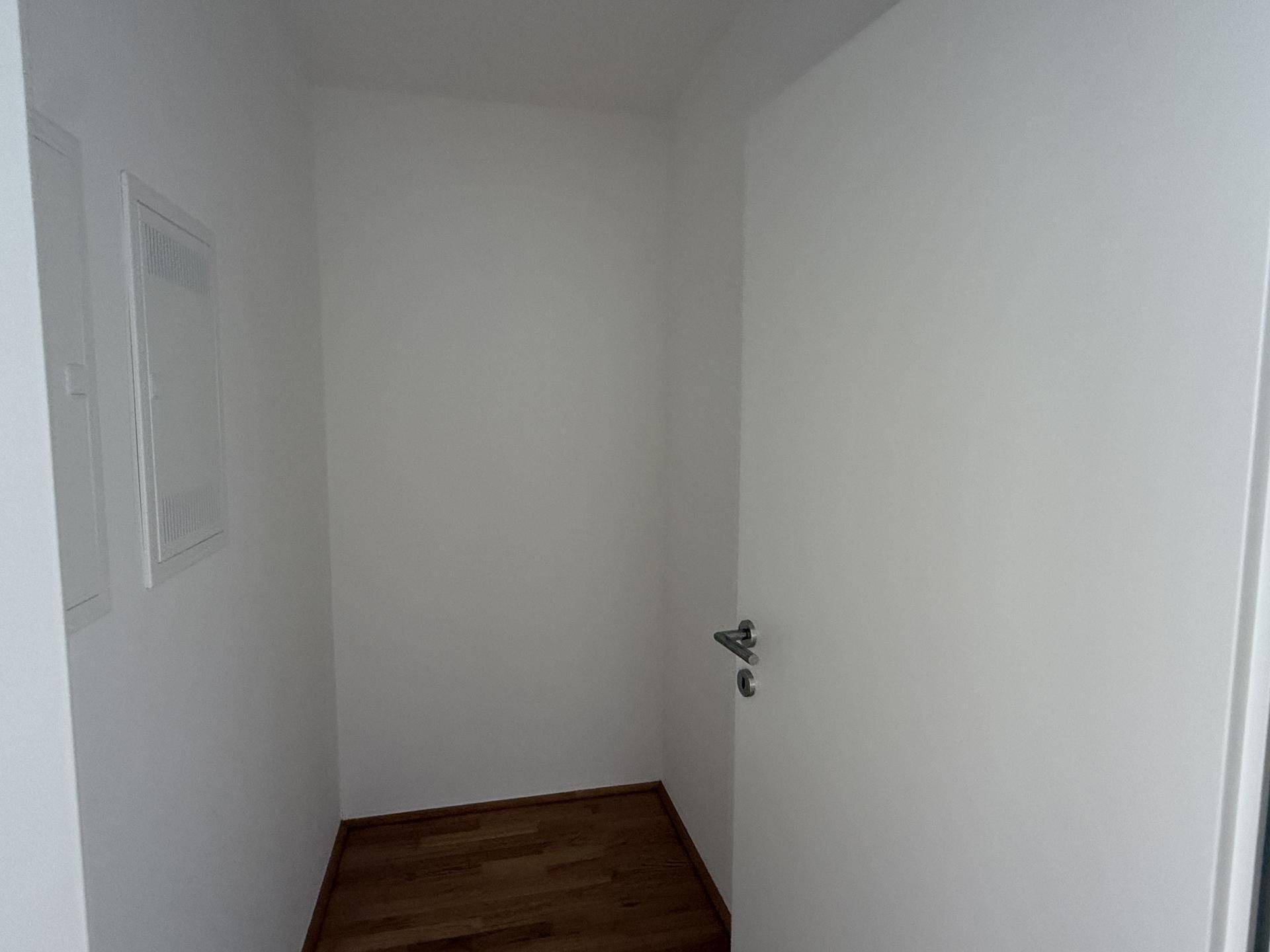 Kleiner, leerer Raum mit Holzboden und weißen Wänden, ideal als Abstellkammer.