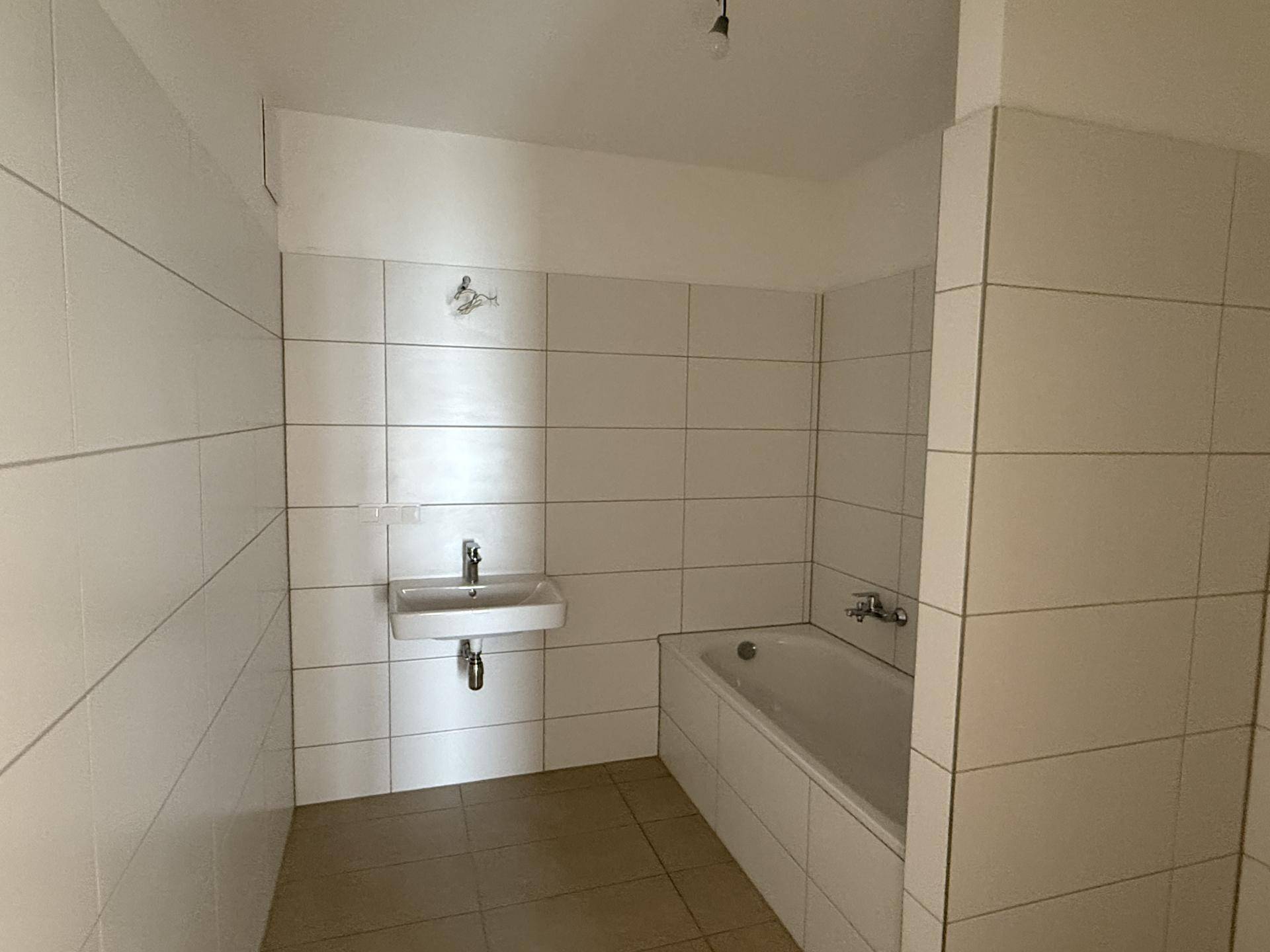 Modernes Badezimmer mit weißen Wandfliesen, Badewanne und einem einzelnen Waschbecken.