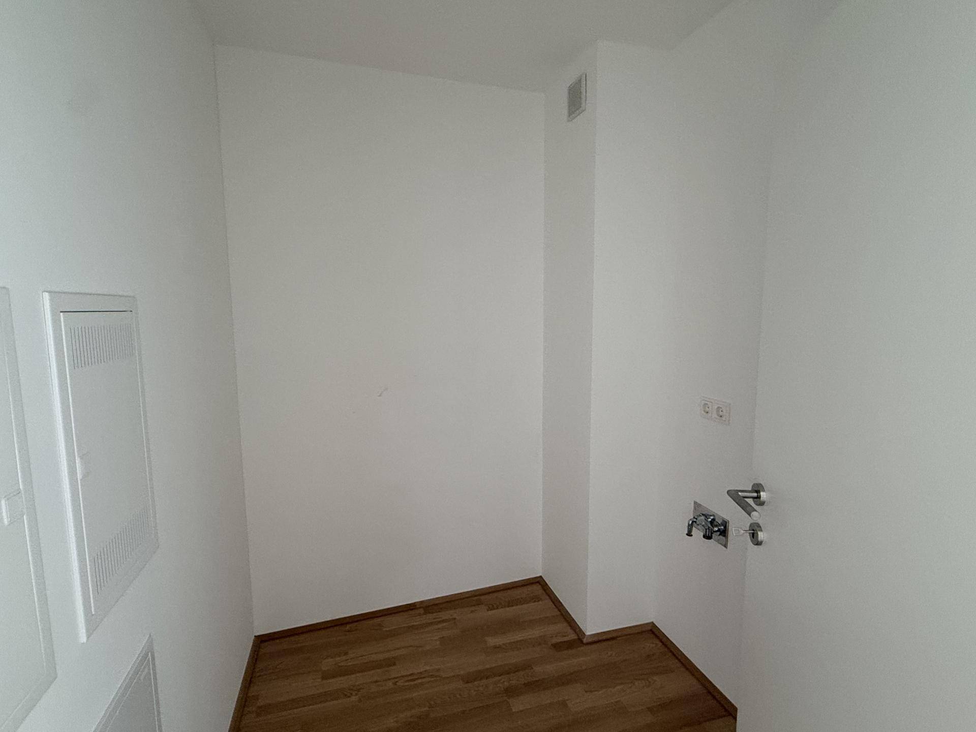 Praktischer Abstellraum mit Parkettboden und Anschlüssen für Haushaltsgeräte.