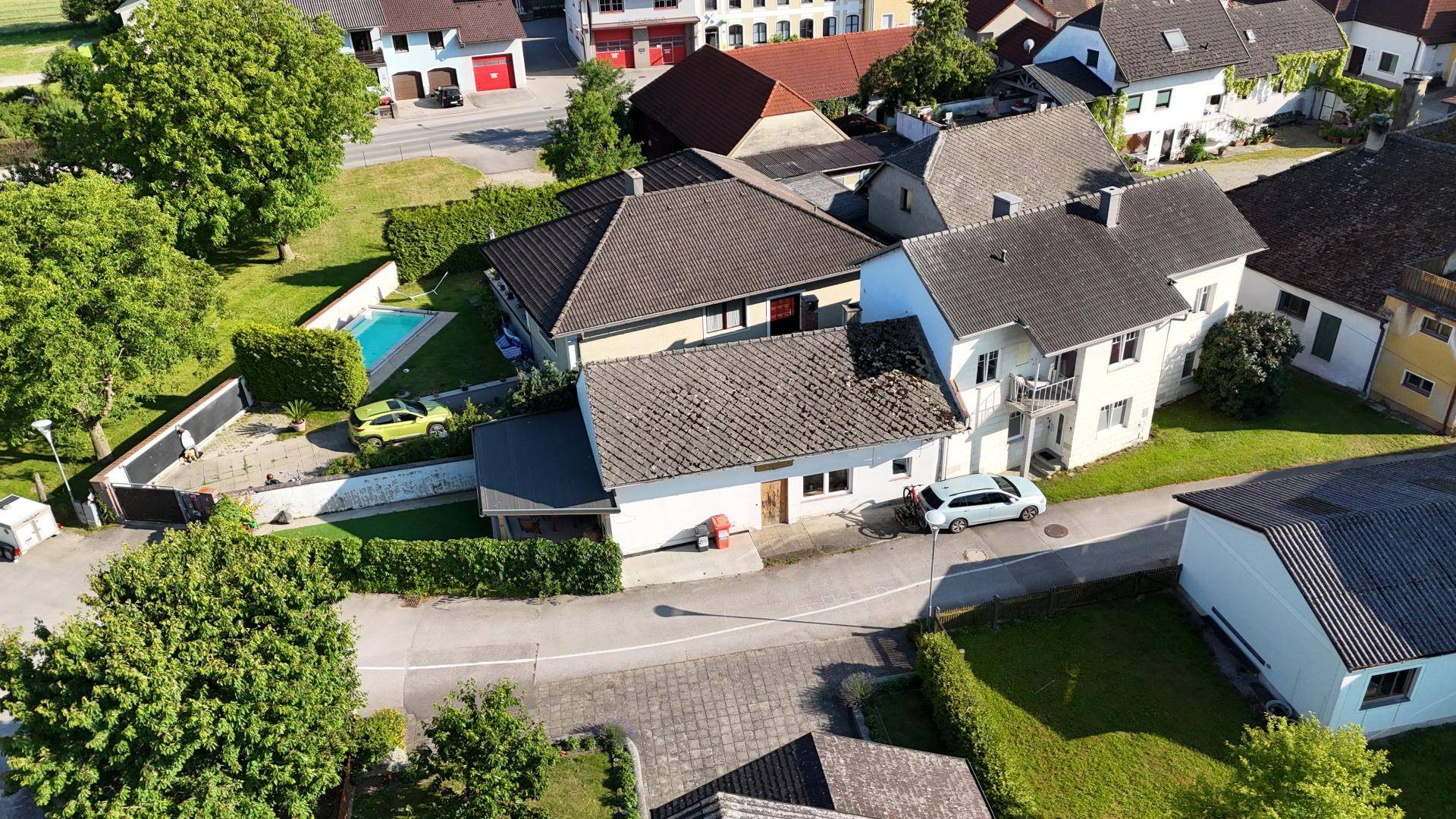 Luftaufnahme einer Wohnsiedlung mit mehreren Häusern, Gärten und einem Swimmingpool.