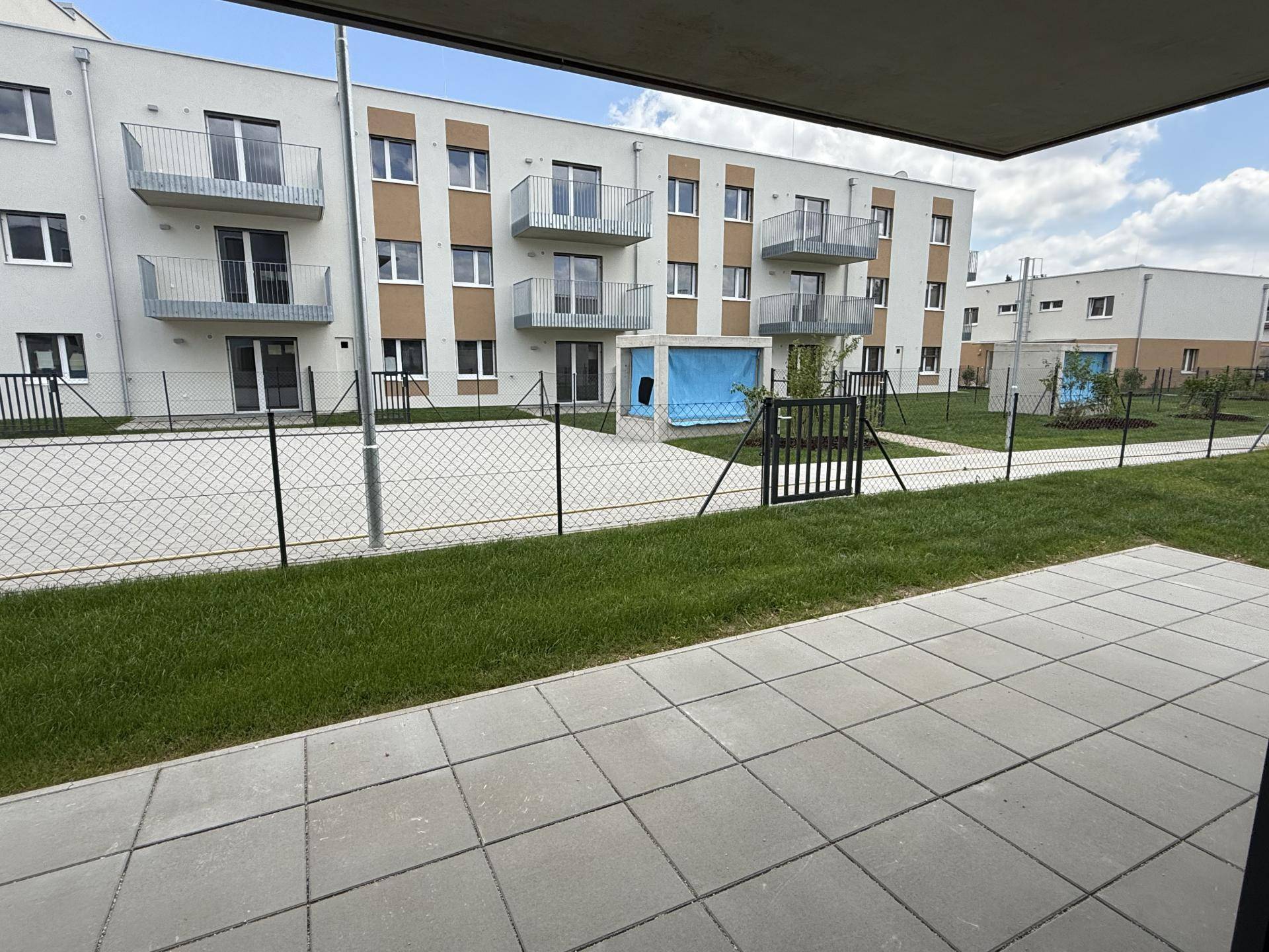 Blick von der Terrasse auf die umliegenden Neubauten und die grüne Rasenfläche.