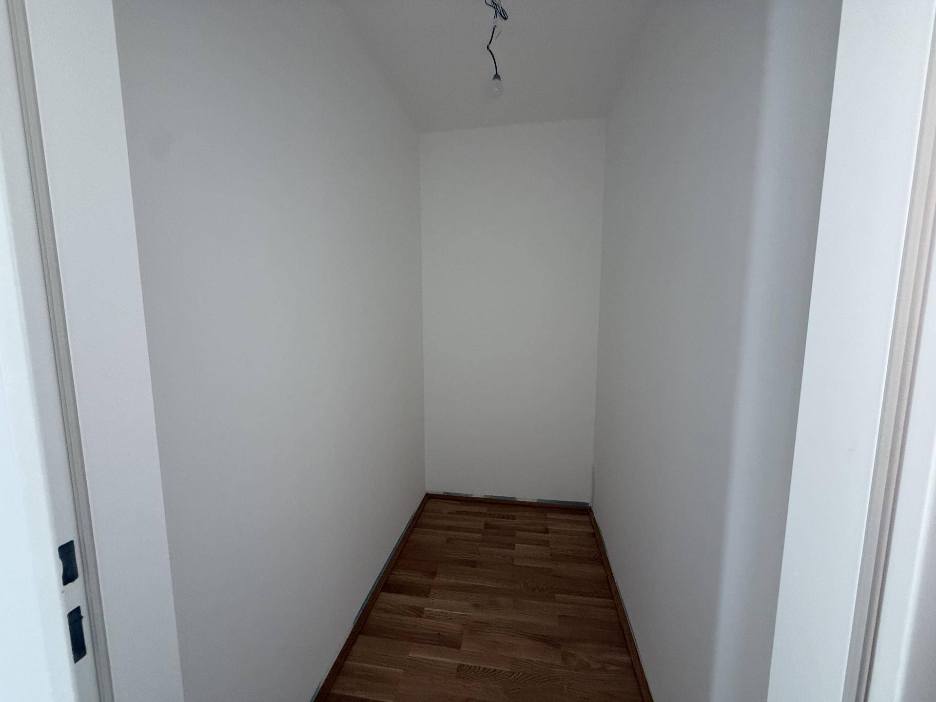 Kleiner Abstellraum mit Holzboden und weißen Wänden, ideal für zusätzlichen Stauraum.