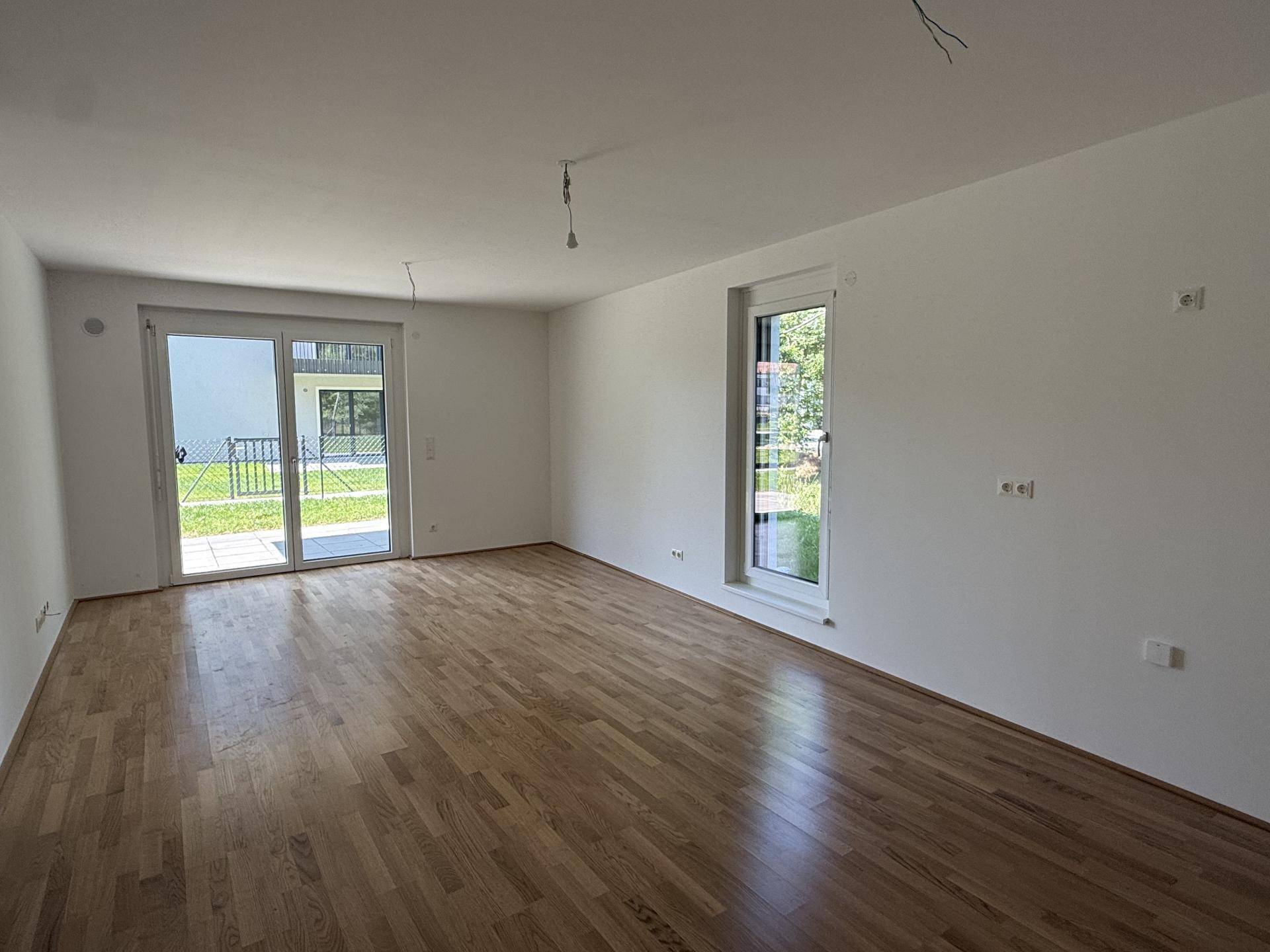 Heller Wohnbereich mit Parkettboden und direktem Zugang zur Terrasse und zum Garten.
