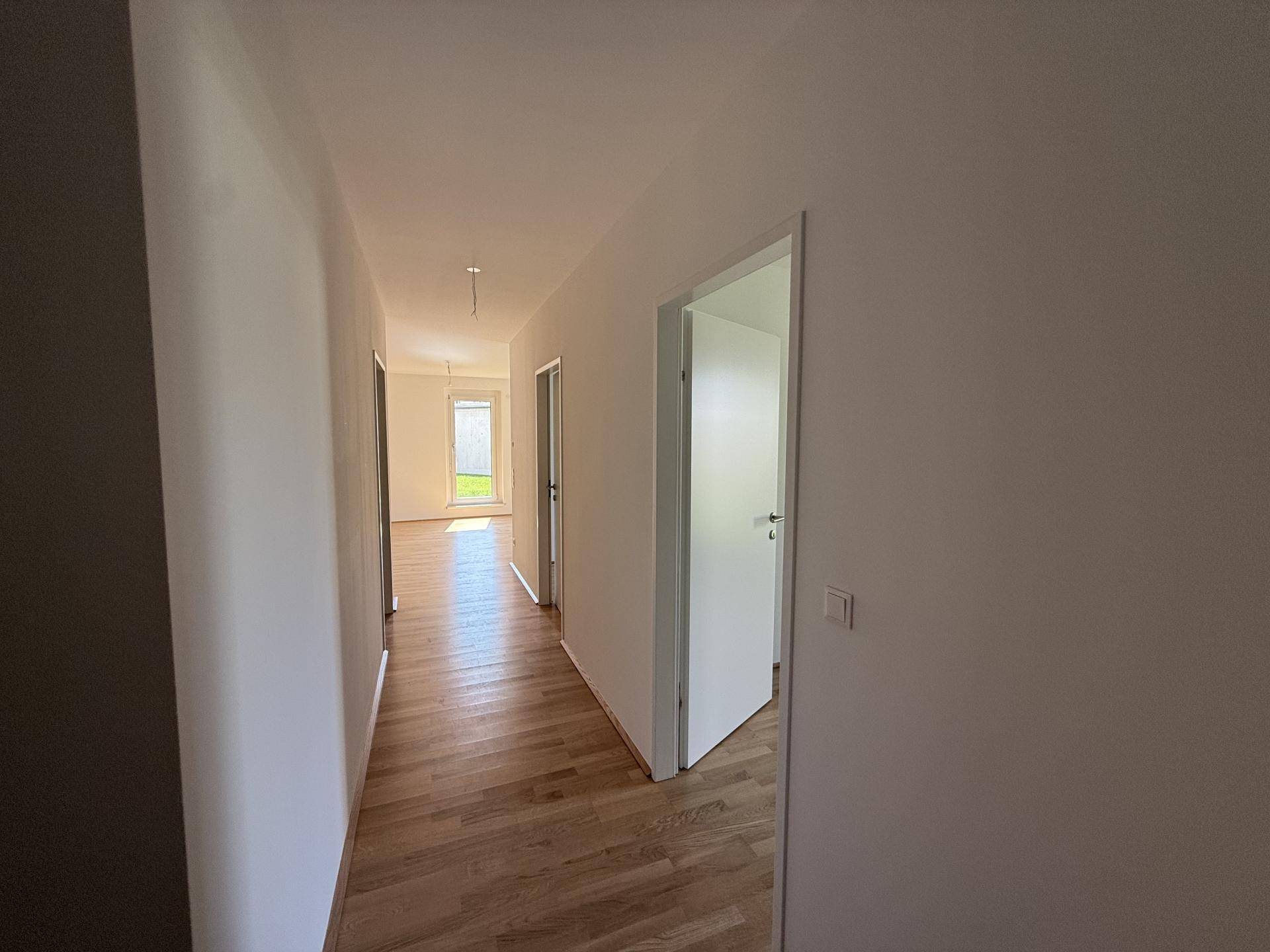 Langer, heller Flur mit Holzboden, der zu verschiedenen Zimmern führt.
