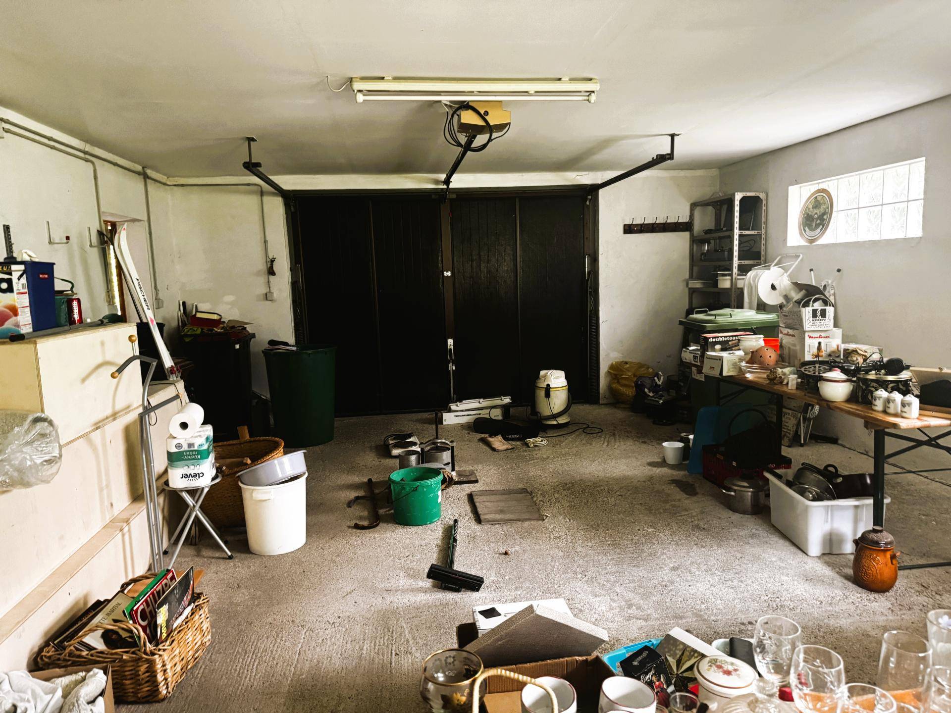 Geräumige Garage mit Betonboden, Stauraum und verschiedenen Haushaltsgegenständen.