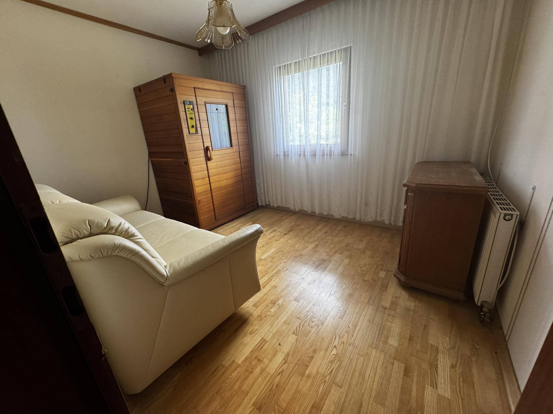 Raum mit Infrarotsauna, Sofa und Holzfußboden, ideal für Entspannung und Wellness.