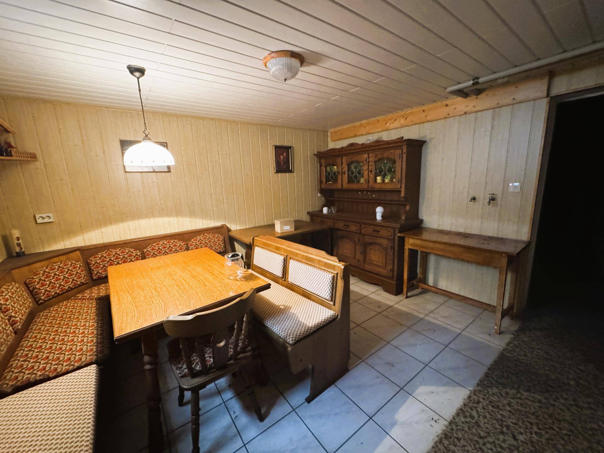 Gemütlicher Kellerraum mit rustikalem Essbereich, Holzvertäfelung und Fliesenboden.