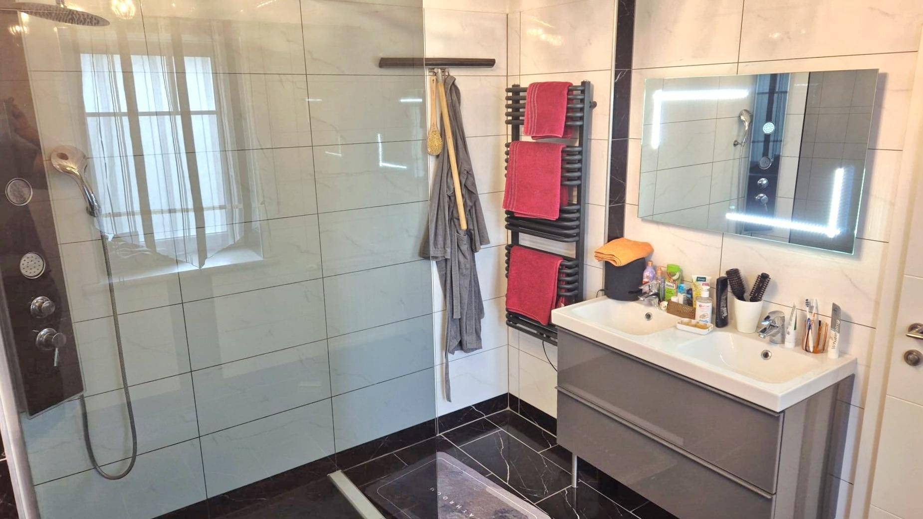 Modernes Badezimmer mit großer begehbarer Dusche, Doppelwaschbecken und beheiztem Handtuchhalter.