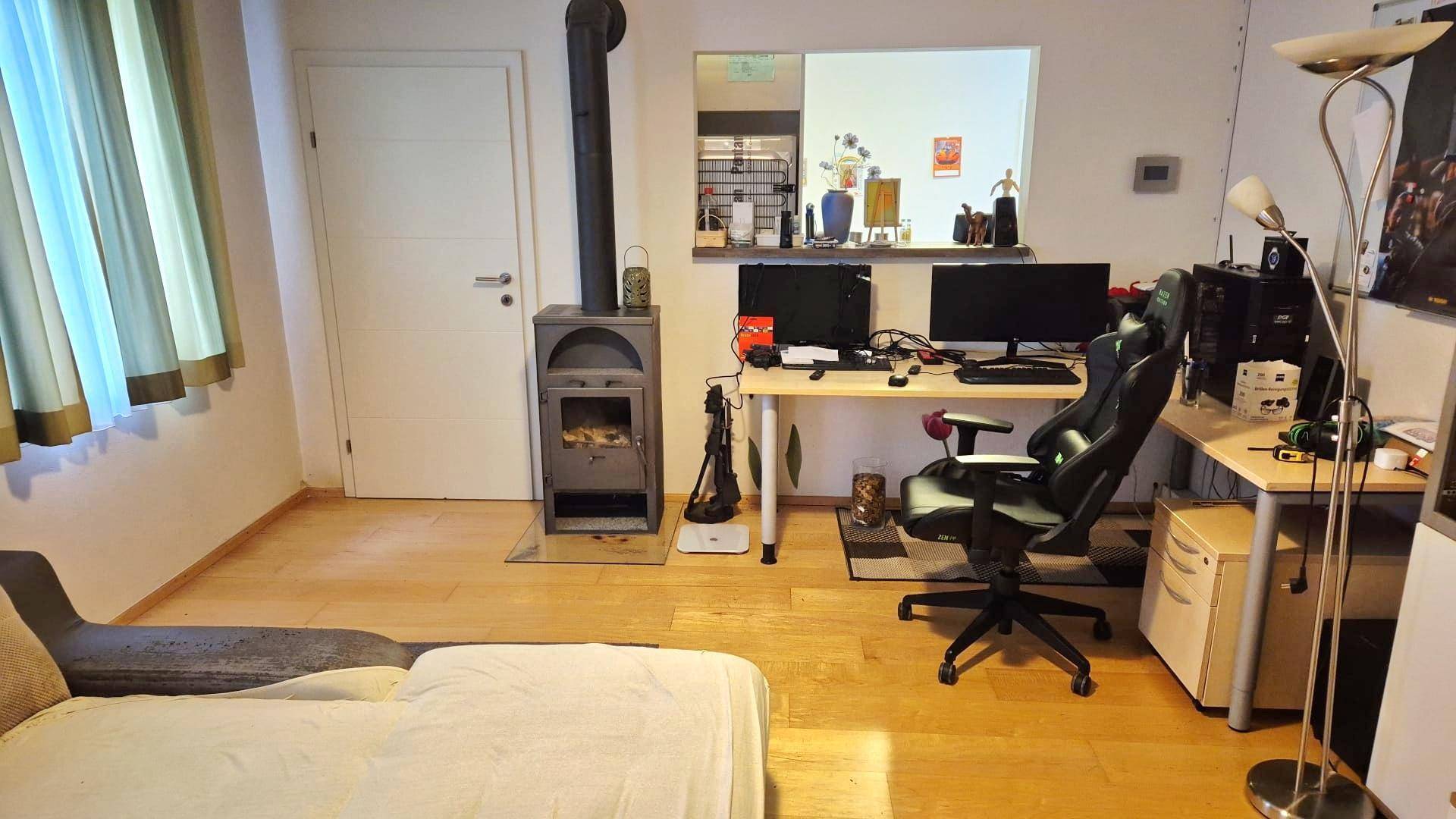 Arbeitszimmer mit Holzboden, Kaminofen und großem Schreibtischbereich.