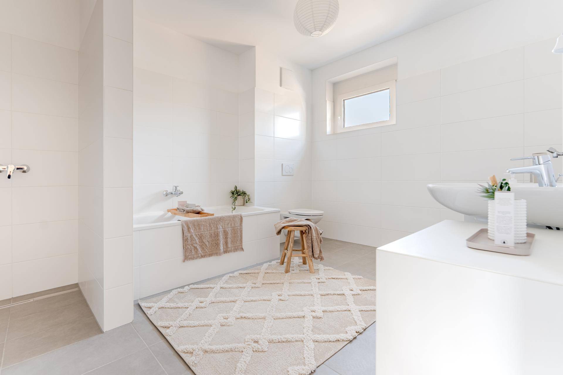 Modernes Badezimmer mit Badewanne, Dusche, Waschbecken und großformatigen Fliesen.