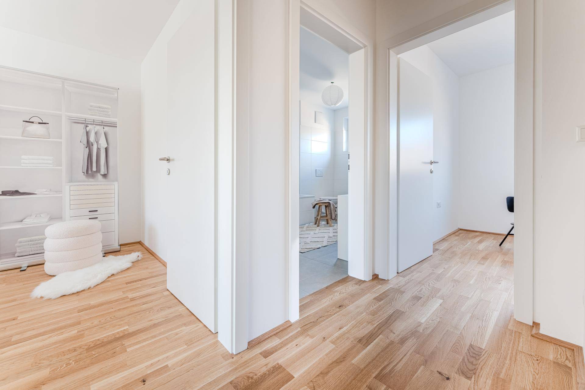 Heller Flur mit Holzboden, der zu Schlafzimmer und Badezimmer führt.