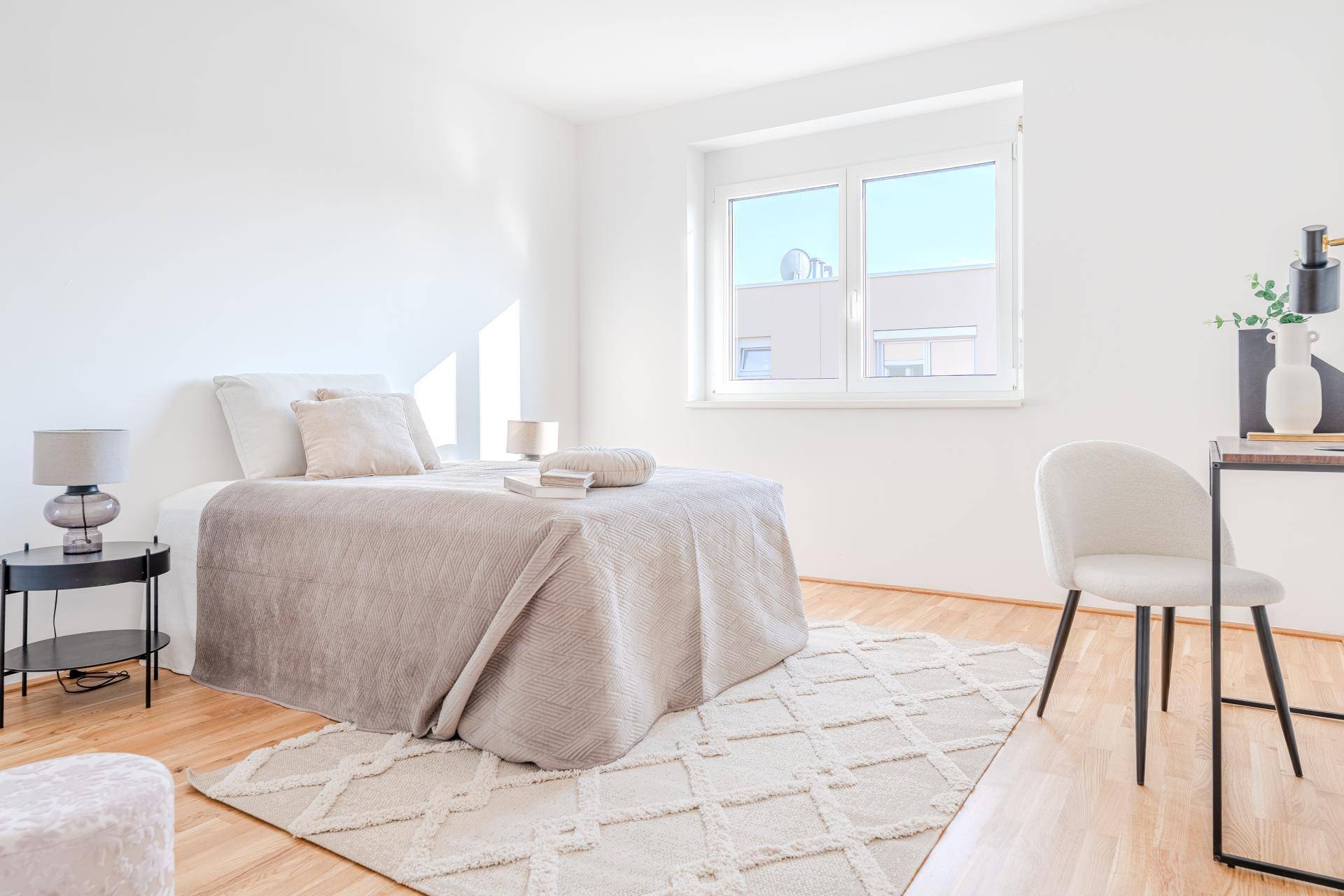 Modern eingerichtetes Schlafzimmer mit Holzboden, großem Fenster und viel Tageslicht.
