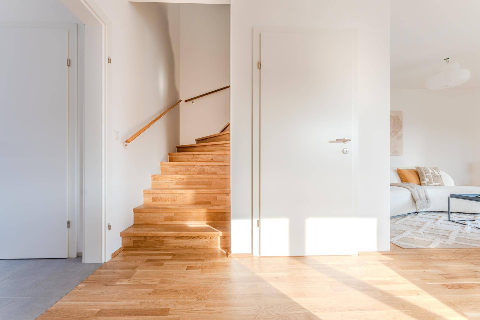 Heller Flur mit Holztreppe und Zugang zum Wohnbereich.