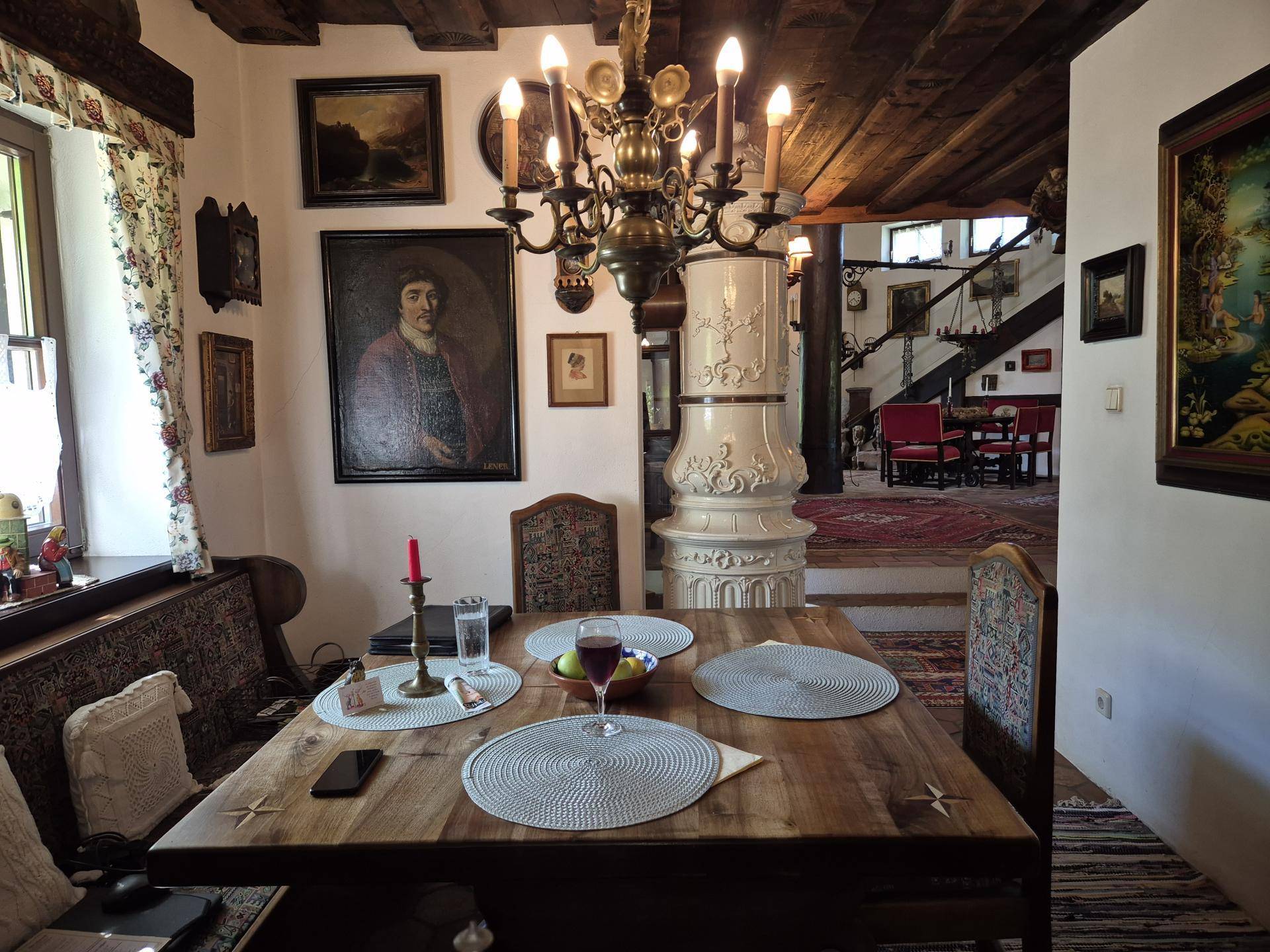 Gemütlicher Essbereich mit Holztisch, traditionellem Kachelofen und Kronleuchter.