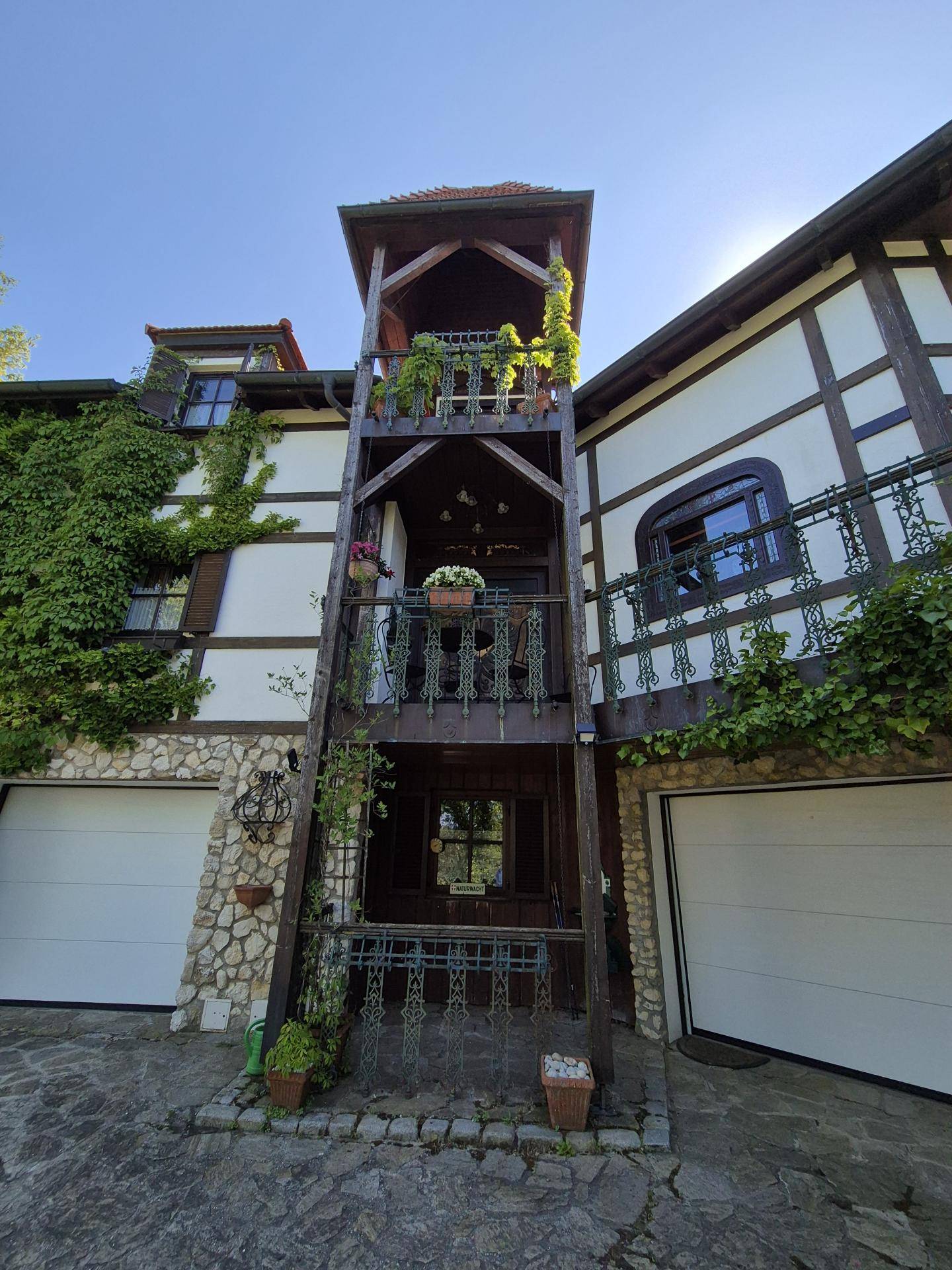 Detailansicht des traditionellen Fachwerkhauses mit Garagen und einem hölzernen Turm mit Balkonen.
