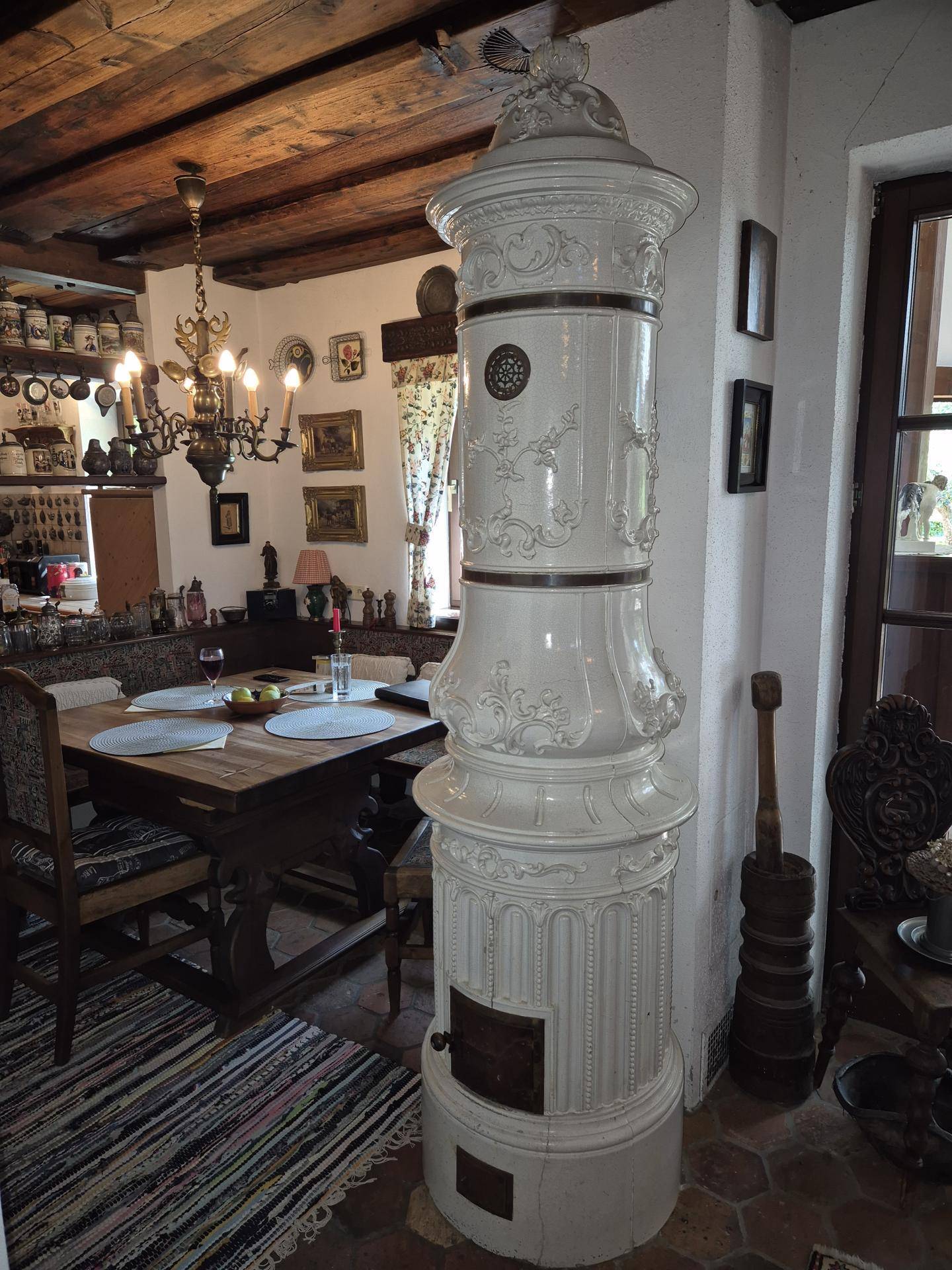 Traditioneller Essbereich mit großem Kachelofen, Holztisch und rustikalem Ambiente.