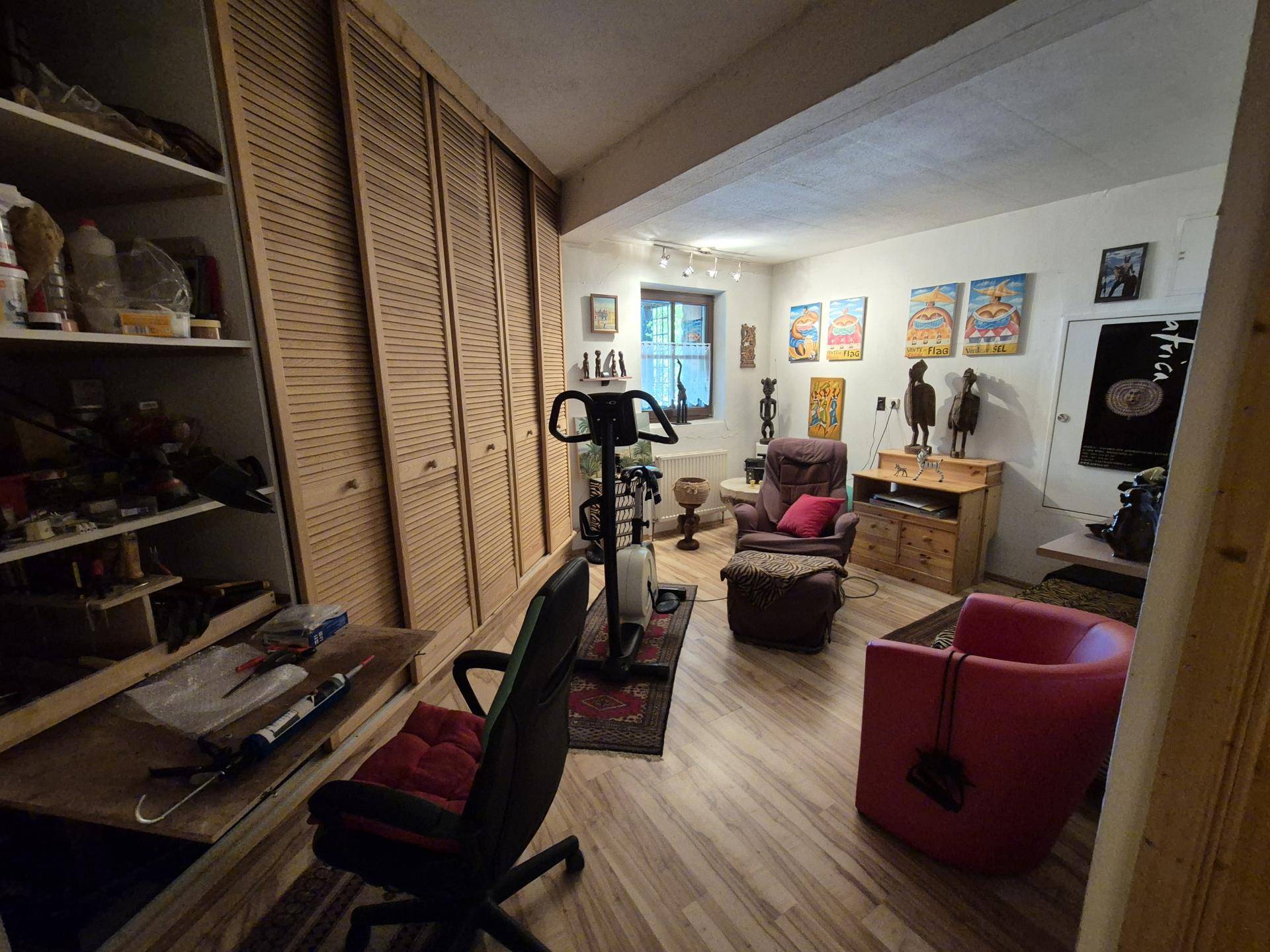 Vielseitiger Raum mit Fitnessgerät, Stauraum und farbenfrohen Kunstwerken an den Wänden.