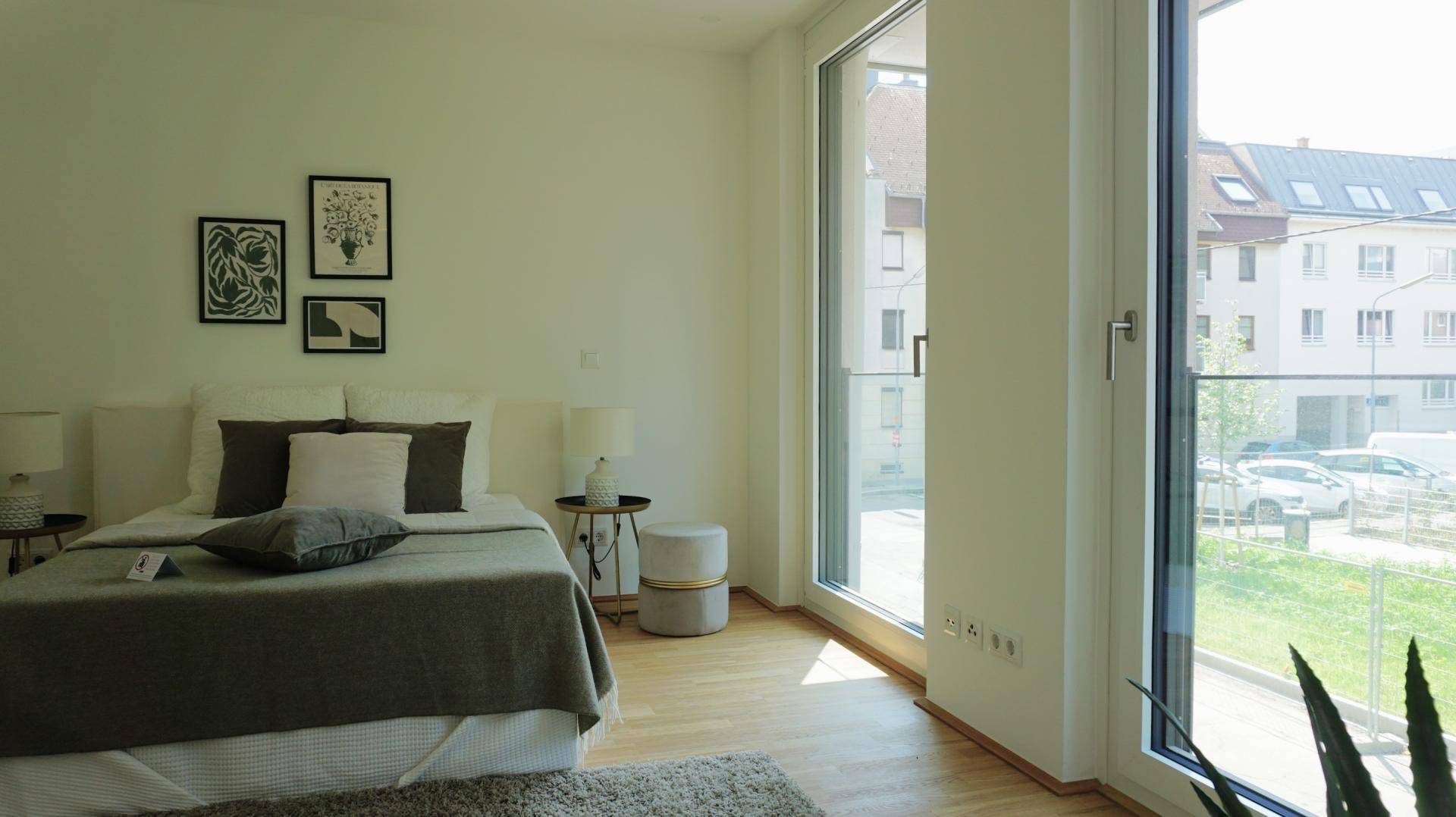 Schlafzimmer mit großen Fenstern, die viel Tageslicht hereinlassen und Blick nach draußen bieten.