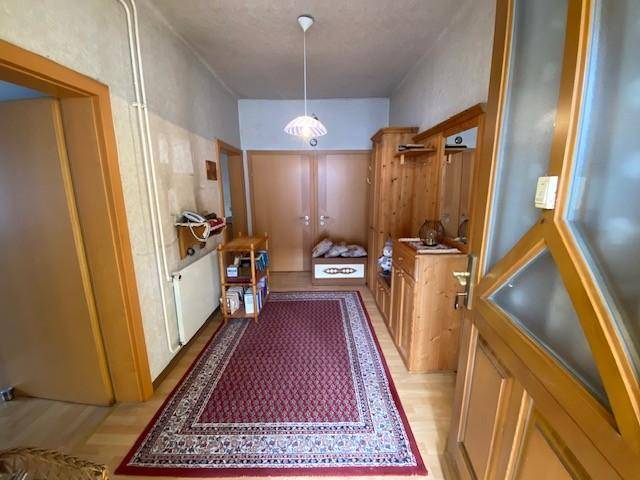 Gemütlicher Flur mit Holzmöbeln, Teppichläufer und heller Deckenleuchte.