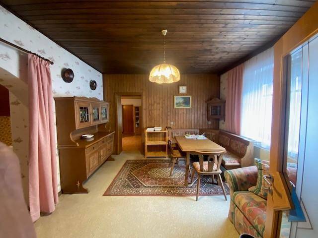 Traditioneller Essbereich mit Holztisch, Eckbank und dunkler Holzdecke.