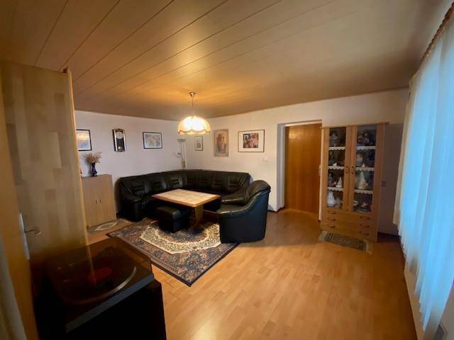 Geräumiges Wohnzimmer mit Ledersofa, Holzboden und Teppich.