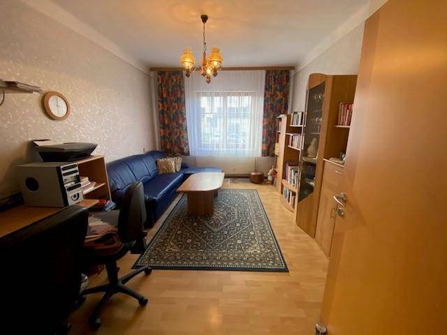 Helles Arbeitszimmer mit Schreibtisch, Bücherregal und Holzboden.