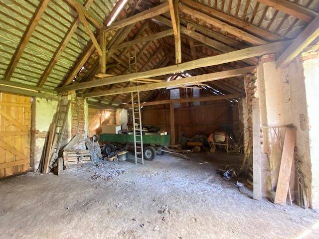Geräumiger Scheuneninnenraum mit Holzbalken, offenem Dachstuhl und Lagerfläche.