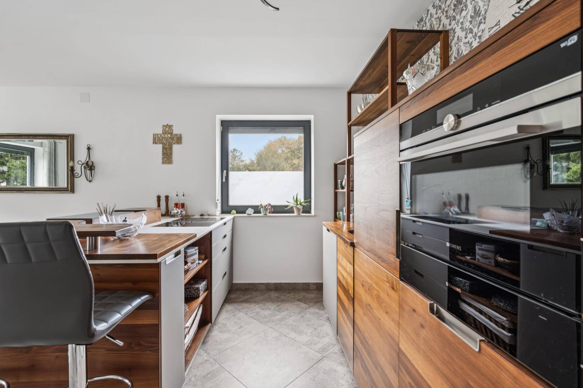Moderne Küche mit Holzelementen, Einbaugeräten und Fenster für natürliches Licht.