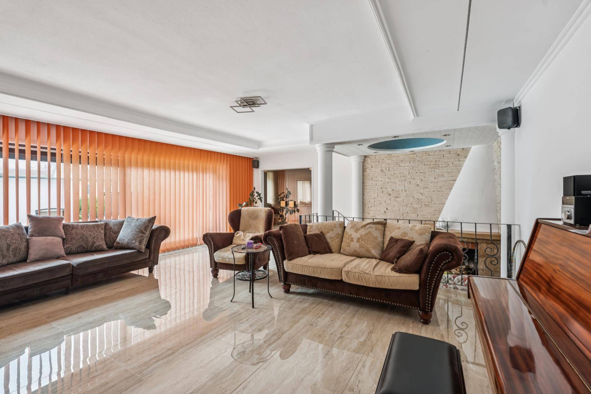 Geräumiges Wohnzimmer mit glänzendem Fliesenboden, bequemen Sofas und Zugang zur Terrasse.
