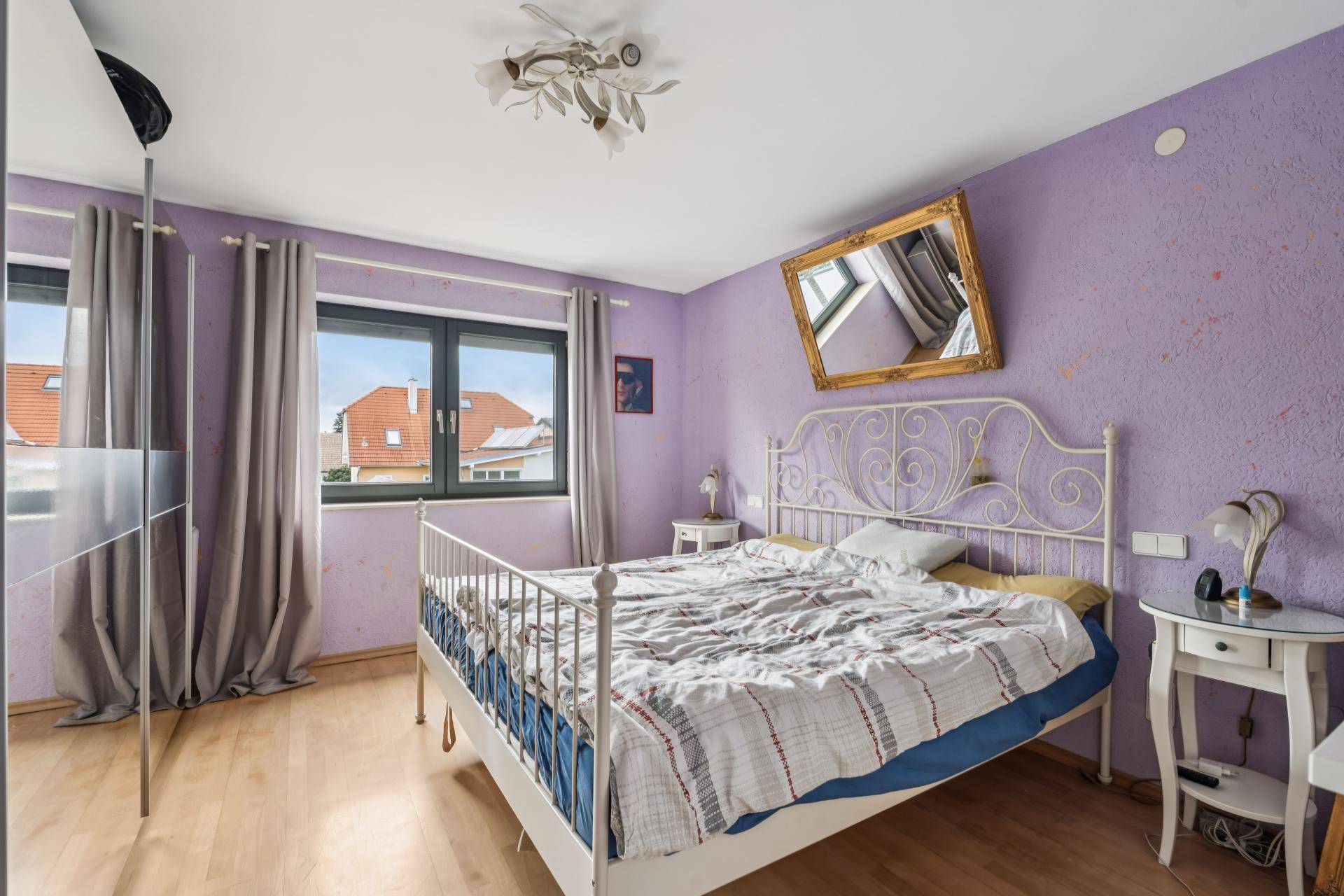 Schlafzimmer mit lila Wänden, Doppelbett und hellem Holzboden.