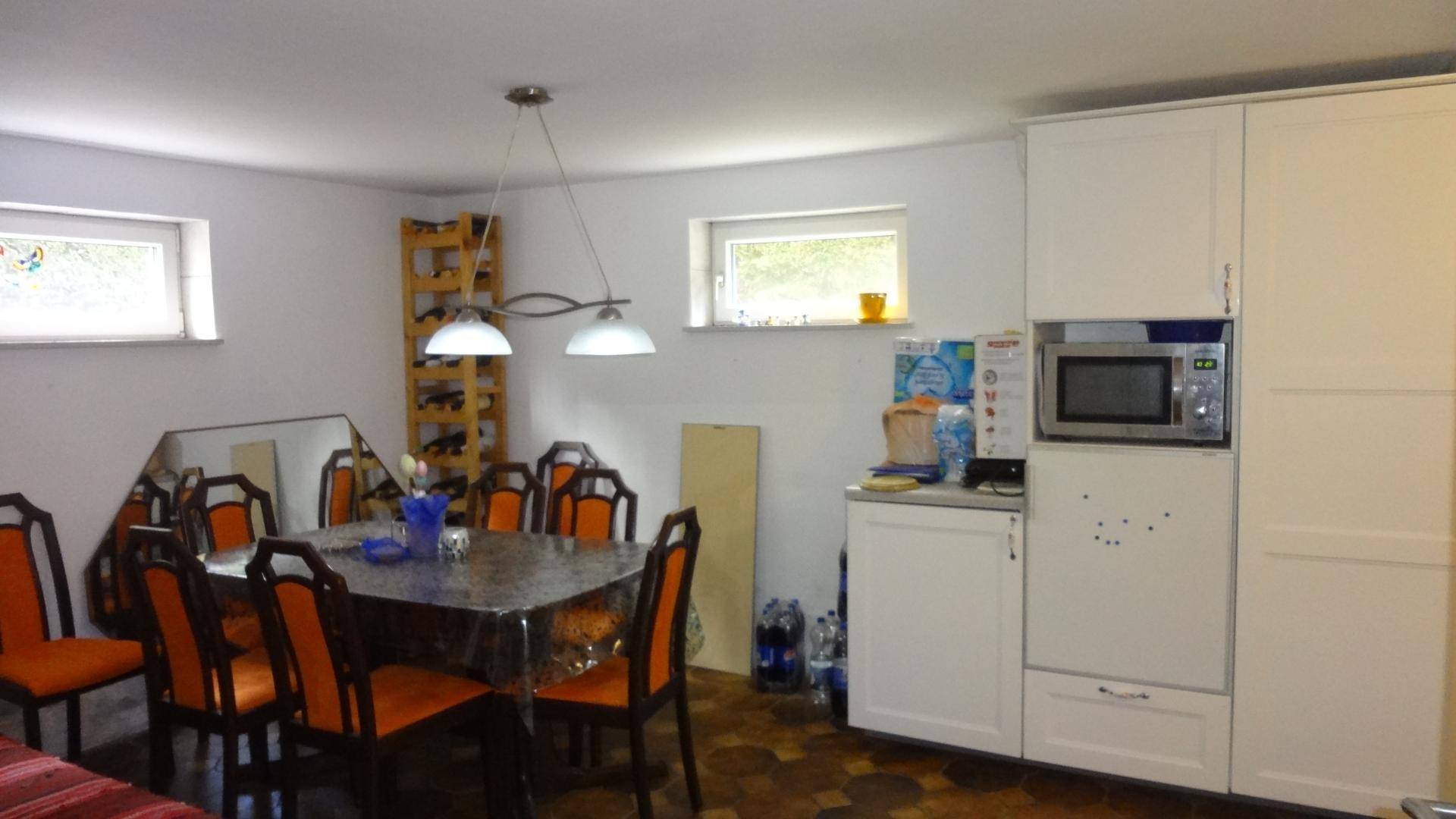 Einfache Küche mit Esstisch, weißen Schränken und Mikrowelle im Untergeschoss.