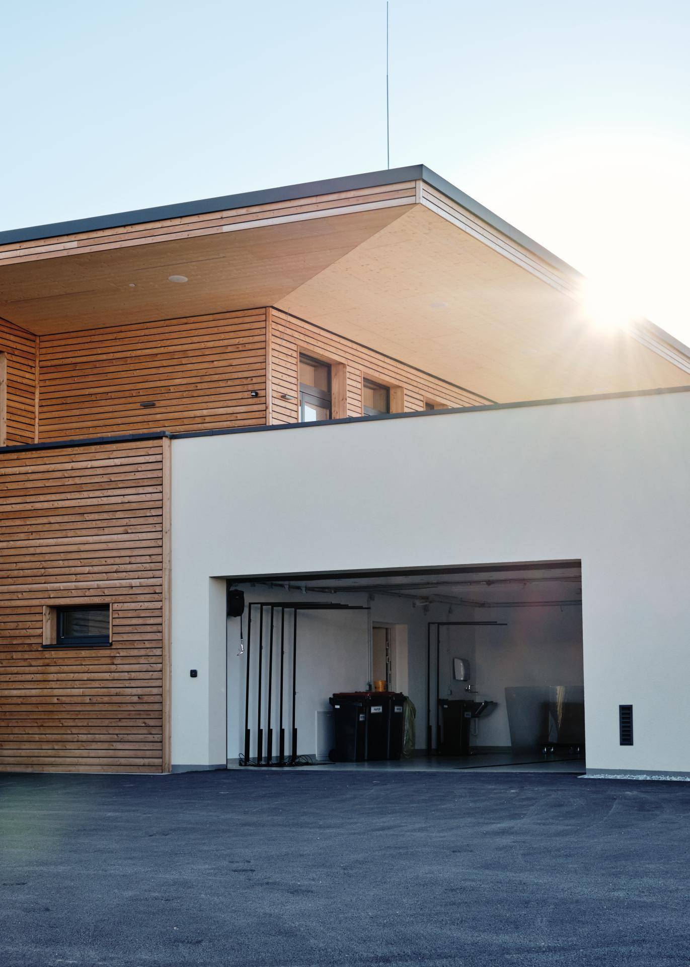 Seitenansicht des Gebäudes mit einer großen Garageneinfahrt und moderner Holzverkleidung.
