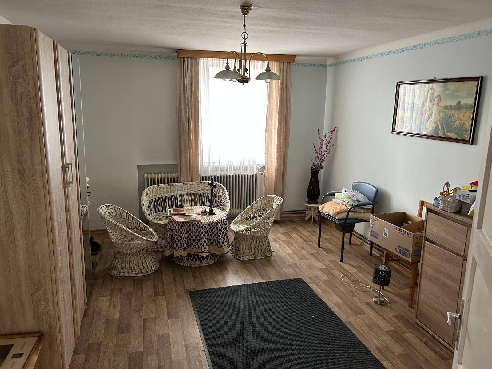 Heller Raum mit Laminatboden, Korbmöbeln und einem Kleiderschrank.