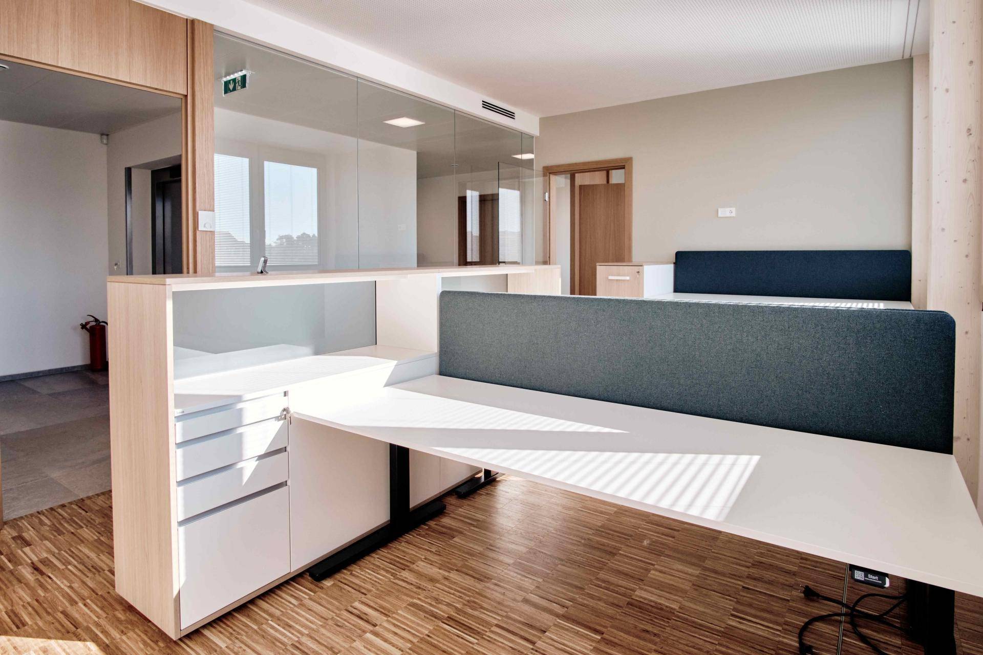 Moderner Büroraum mit ergonomischen Schreibtischen, integrierten Ablagen und viel Tageslicht.