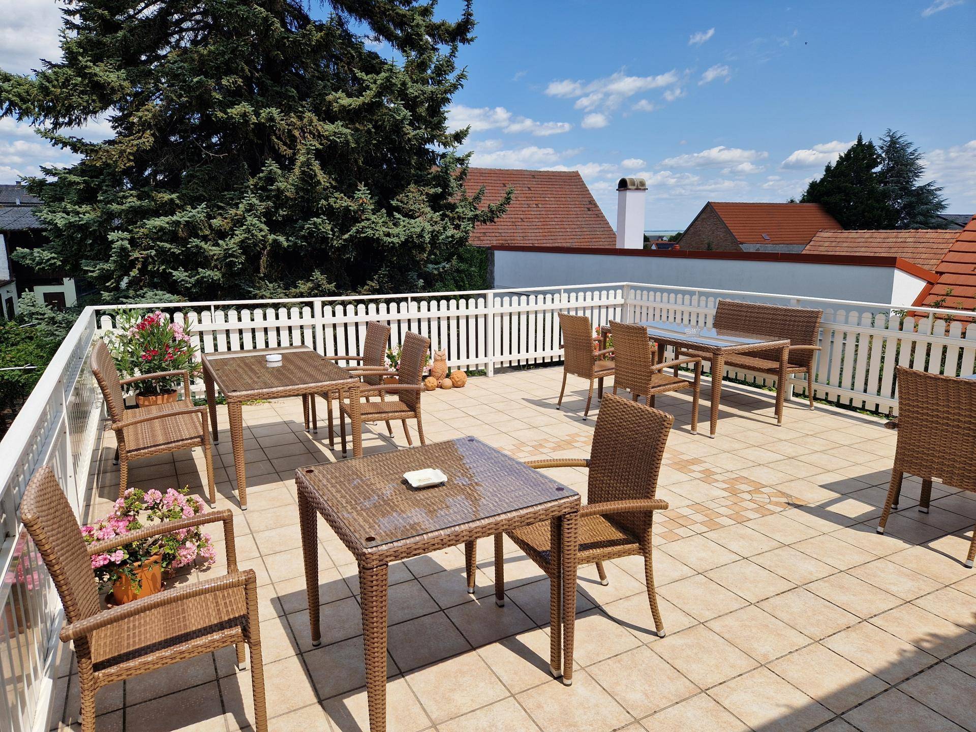 Weitläufige Dachterrasse mit Korbmöbeln und Blick auf die Umgebung unter blauem Himmel.