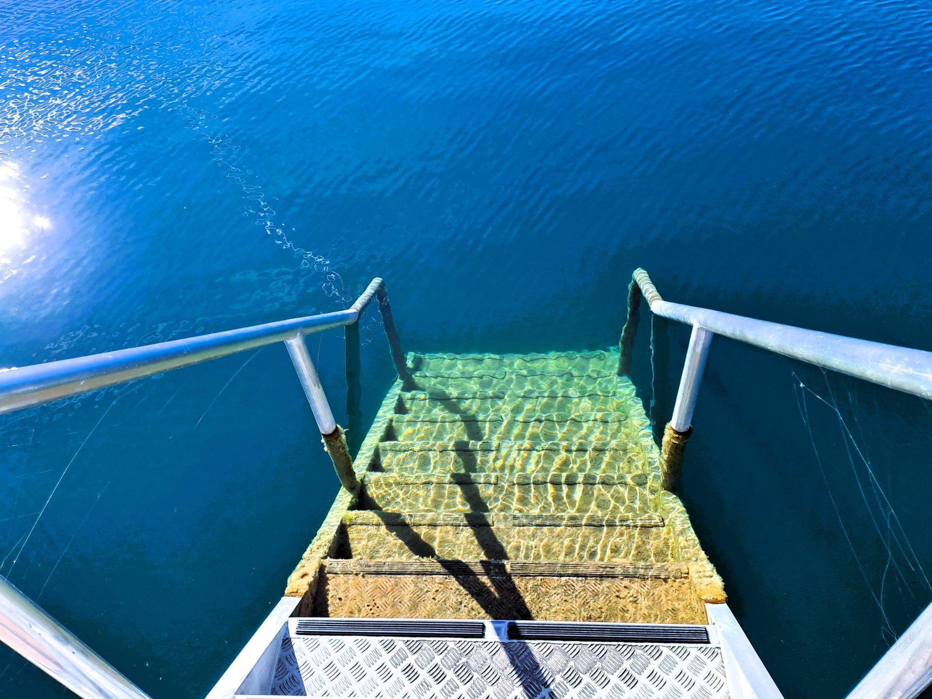 Eine Treppe führt direkt ins klare, einladende Seewasser, ideal für ein erfrischendes Bad.