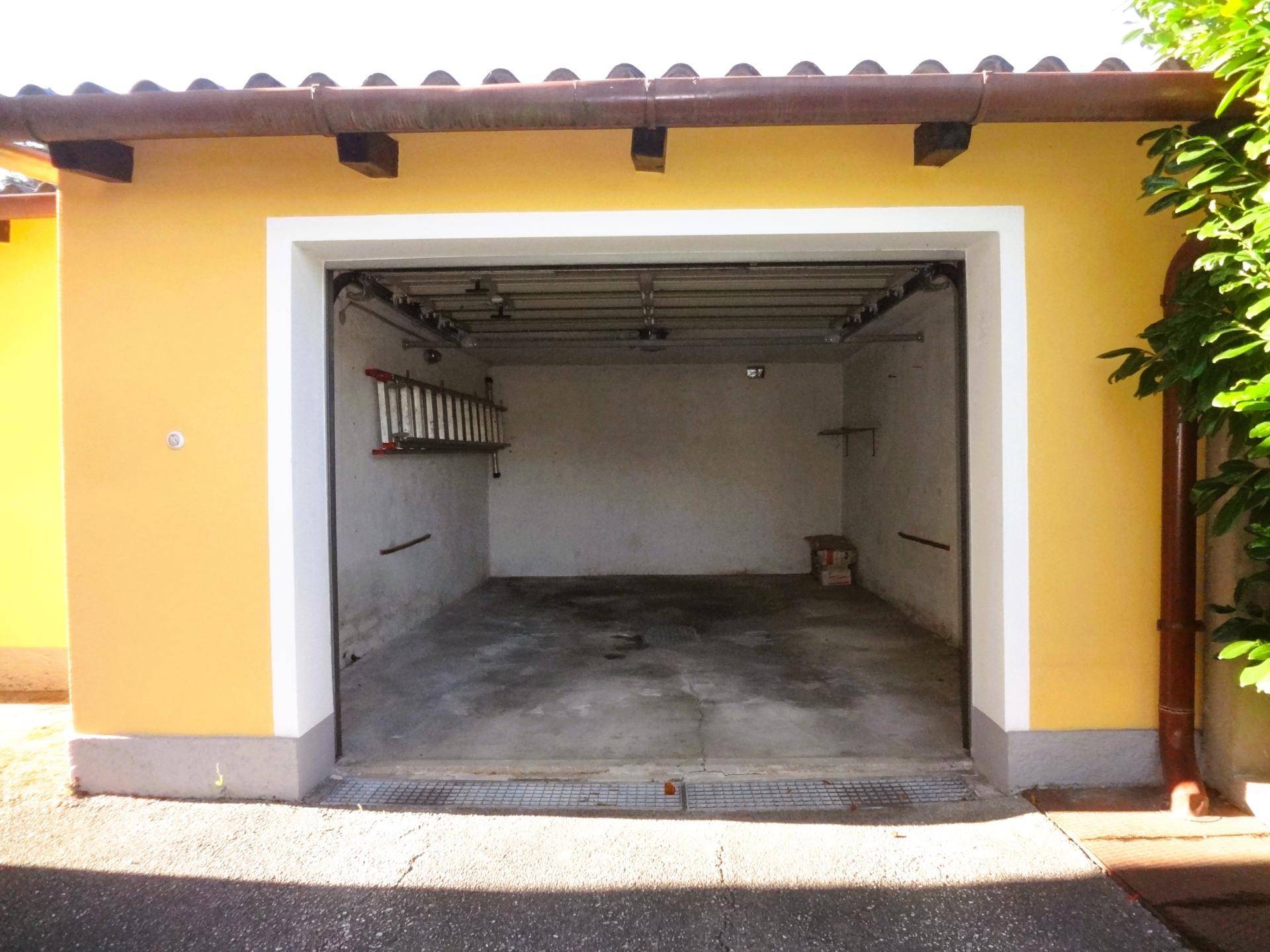 Einzelgarage mit offenem Tor und Betonboden.