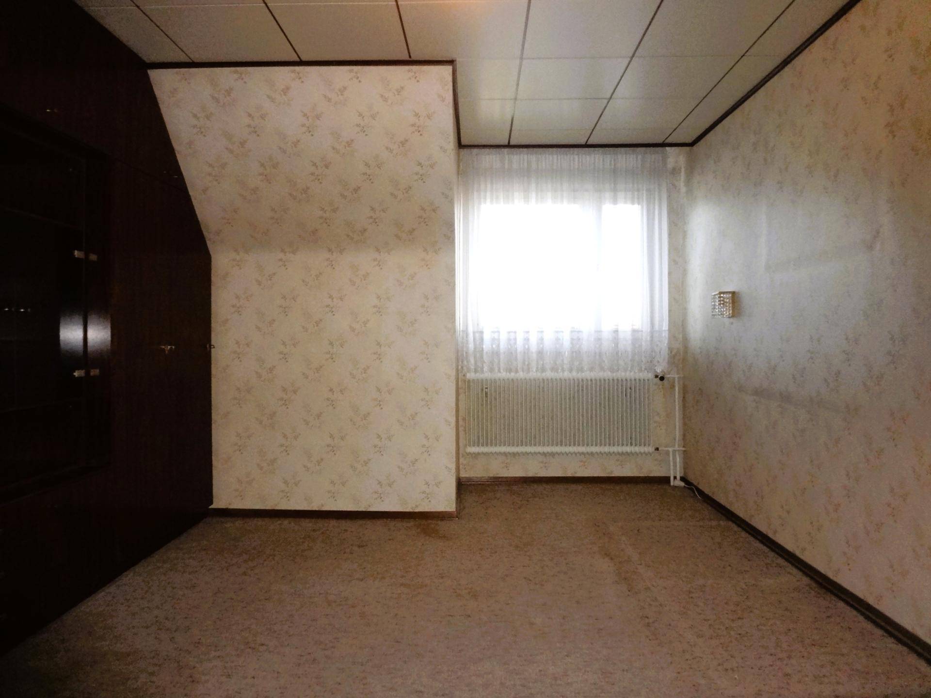 Schlafzimmer mit Teppichboden, gemusterter Tapete und Fenster.