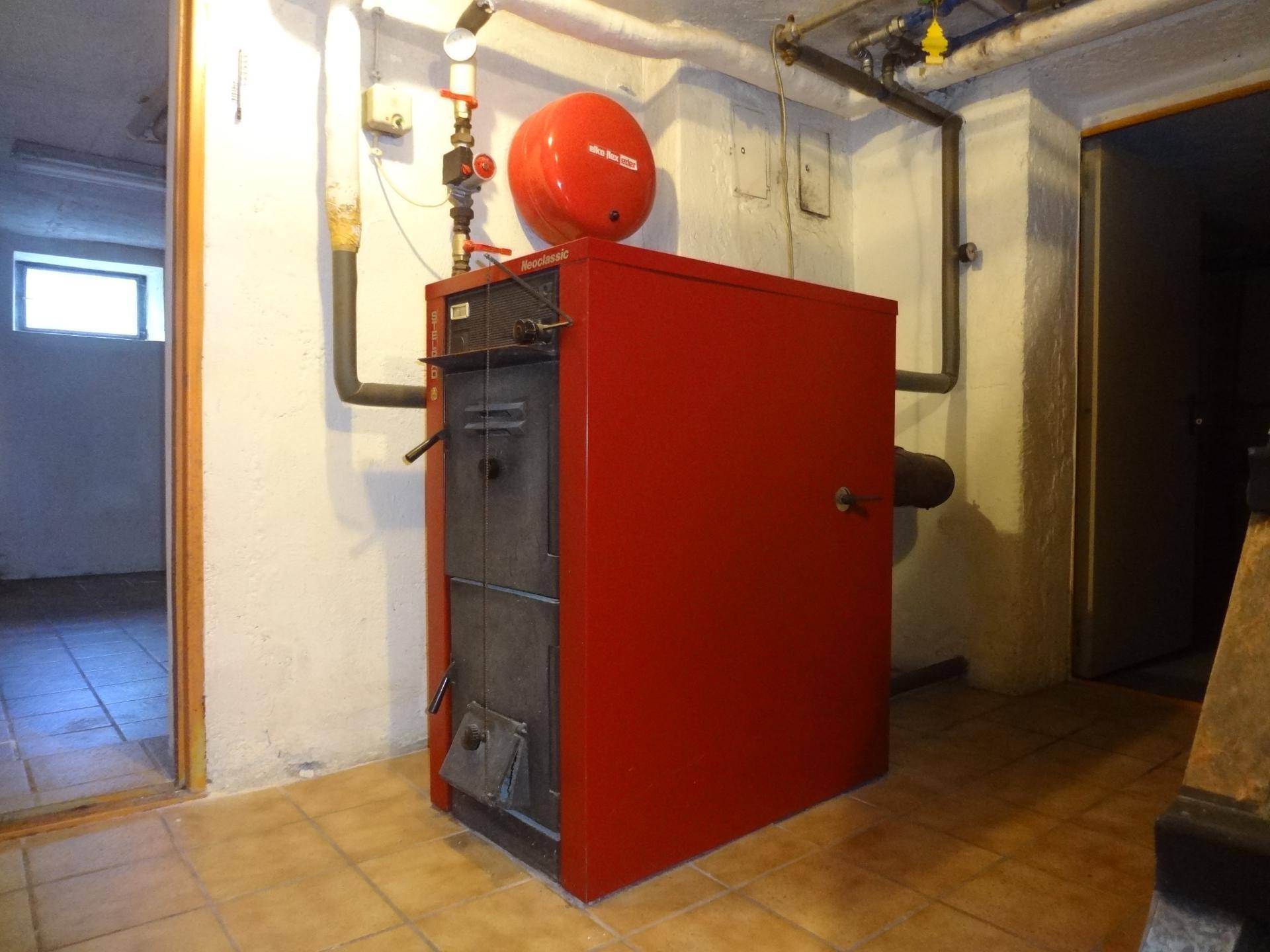 Heizungsraum im Keller mit großem Heizkessel und Warmwasserspeicher.