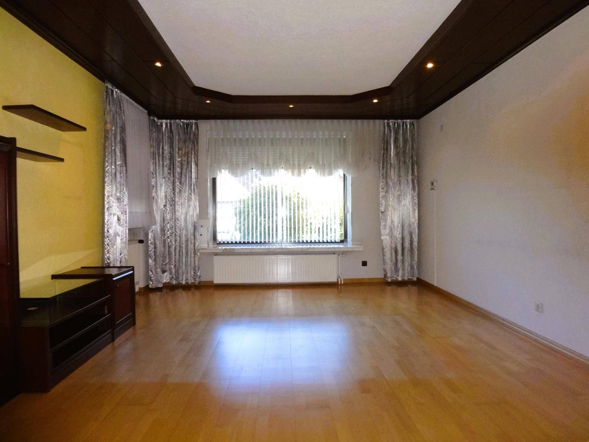 Geräumiges Wohnzimmer mit Parkettboden, großen Fenstern und Holzdeckenverkleidung.