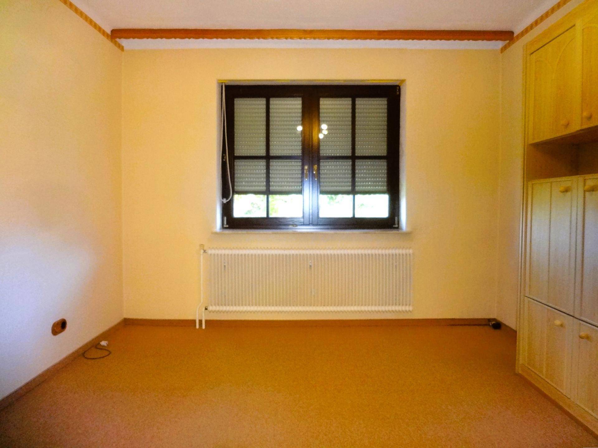 Schlafzimmer mit Teppichboden, Fenster mit Rollladen und Einbauschränken.