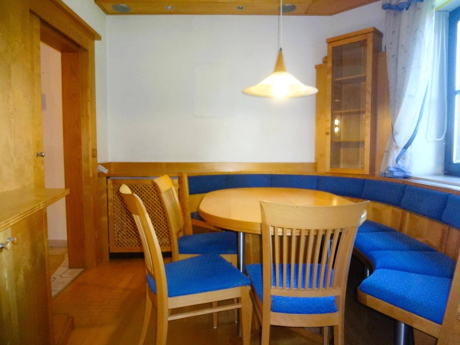 Gemütlicher Essbereich mit Holztisch, blauen Sitzbänken und Holzvertäfelung.
