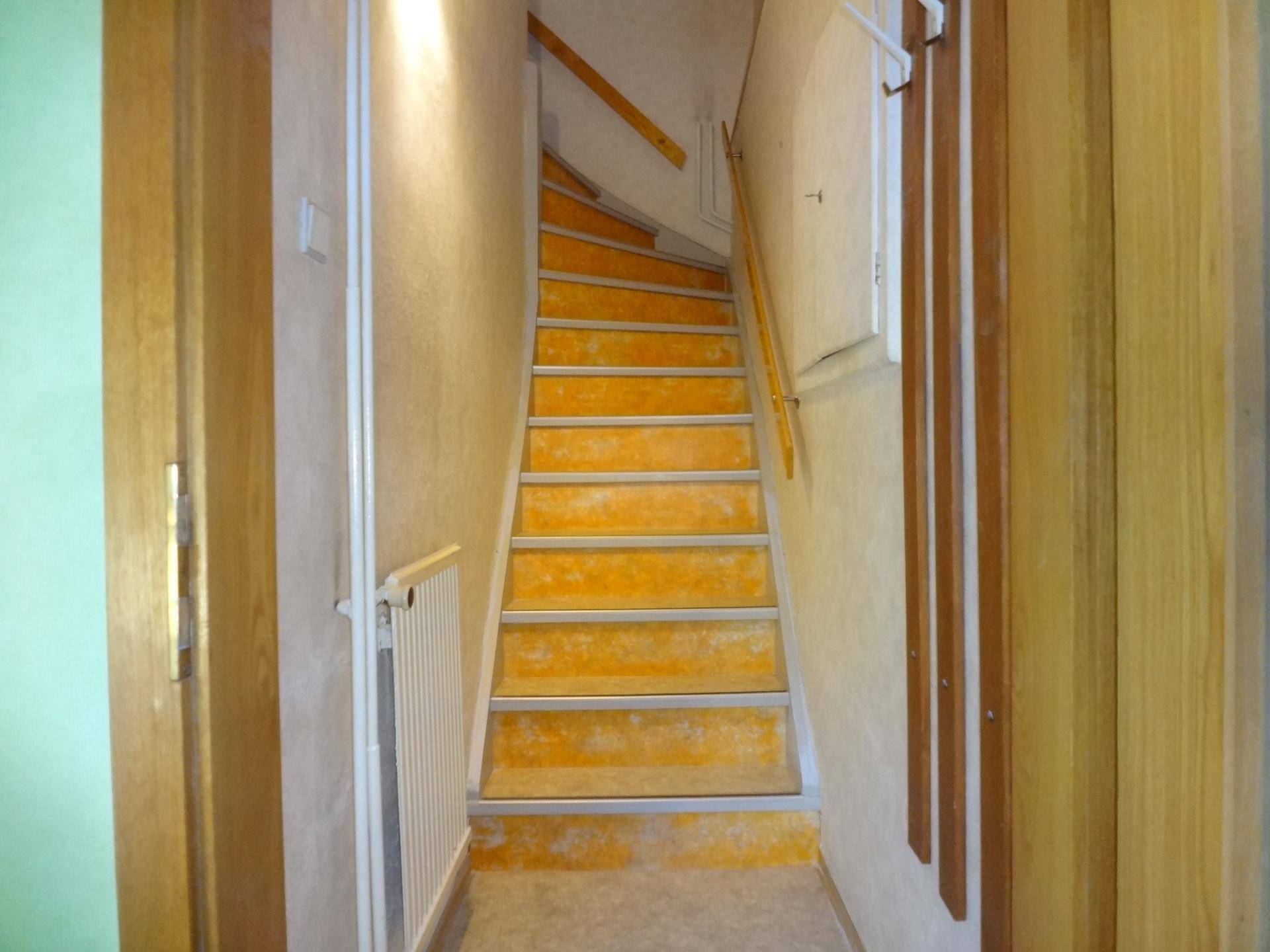 Treppenhaus mit Teppichstufen und Heizkörper, das in ein Obergeschoss führt.